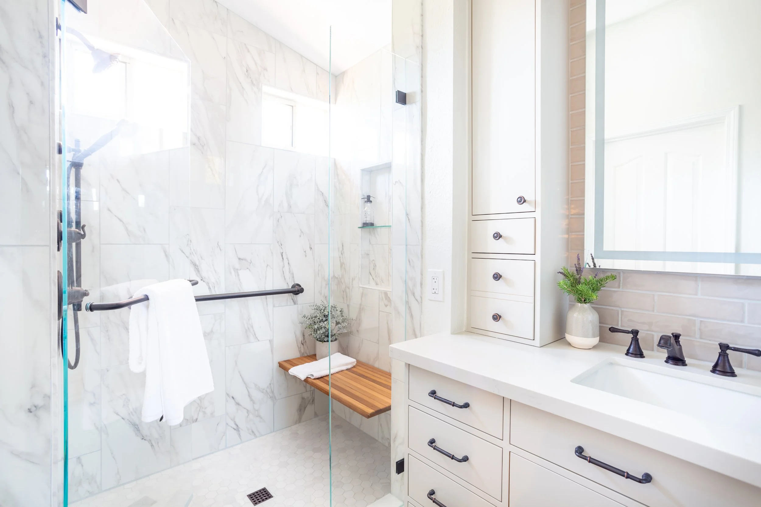 Luxury marble shower with built-in bench and discreet grab bar, blending aging-in-place safety features with timeless bathroom design.
