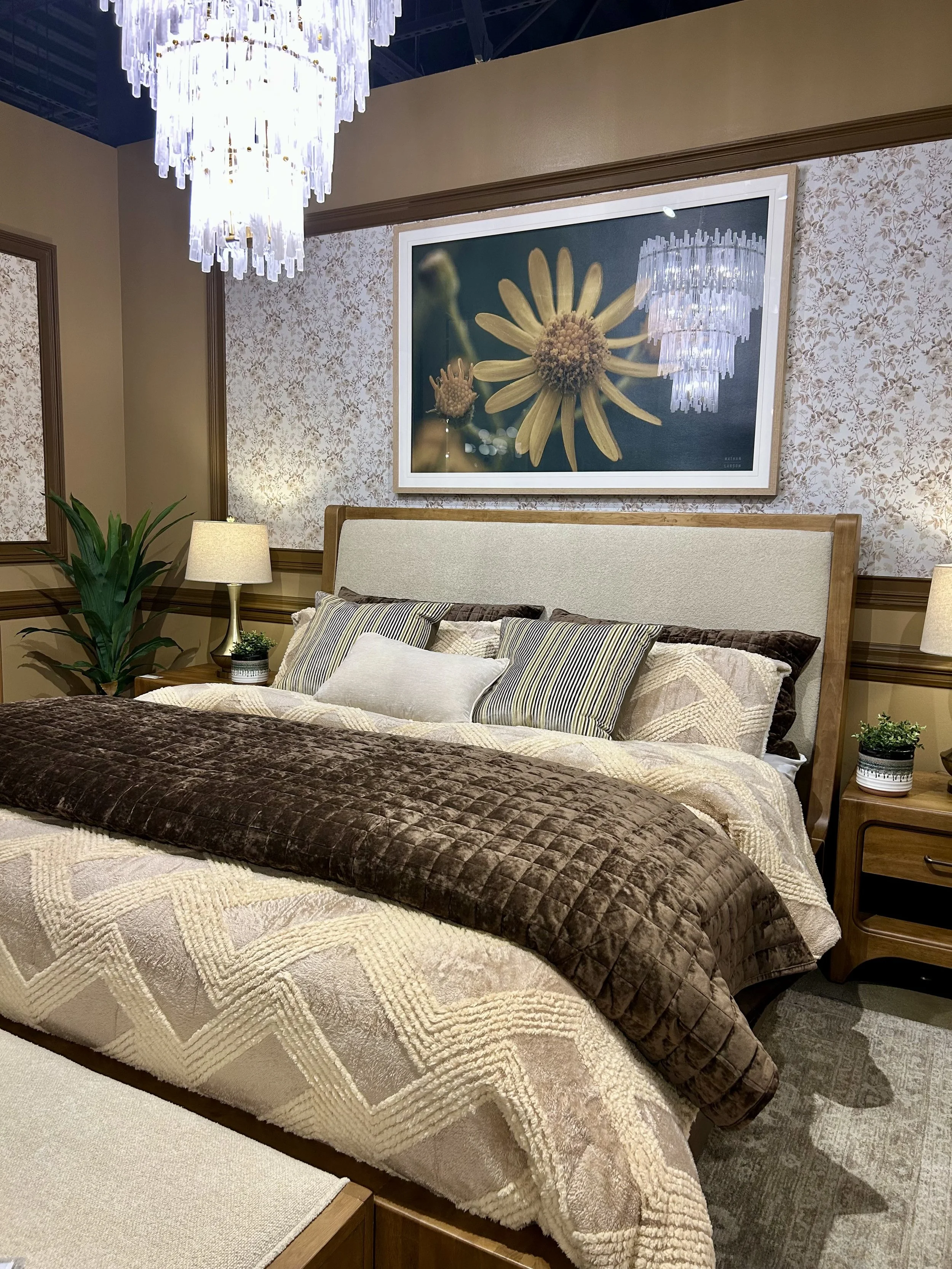 Warm wood bed and nightstands layered with chocolate brown and cream bedding at Las Vegas Market.