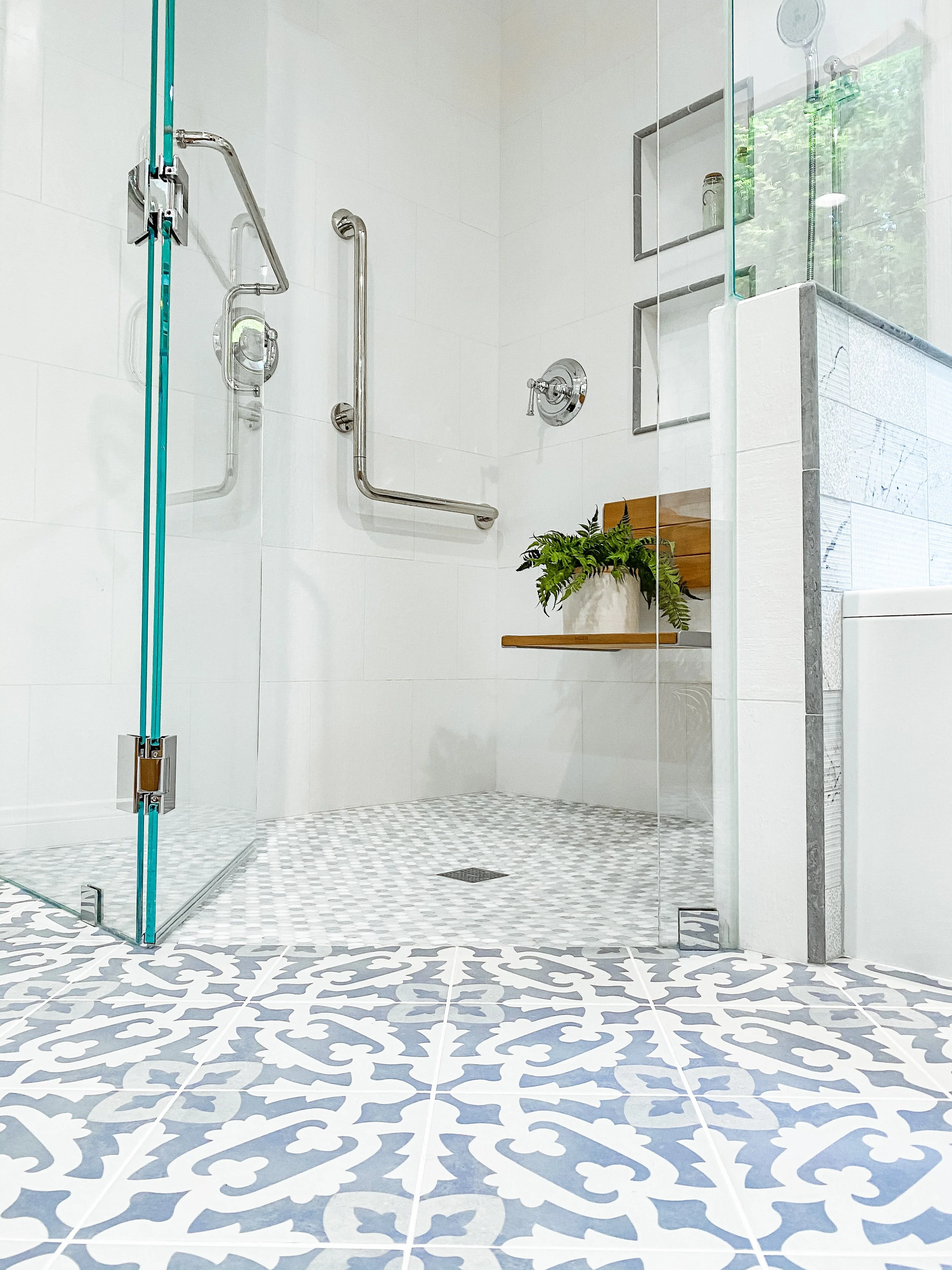 Barrier-free curbless shower with wall-mounted grab bars, built-in bench, and slip-resistant tile flooring designed for aging-in-place safety.