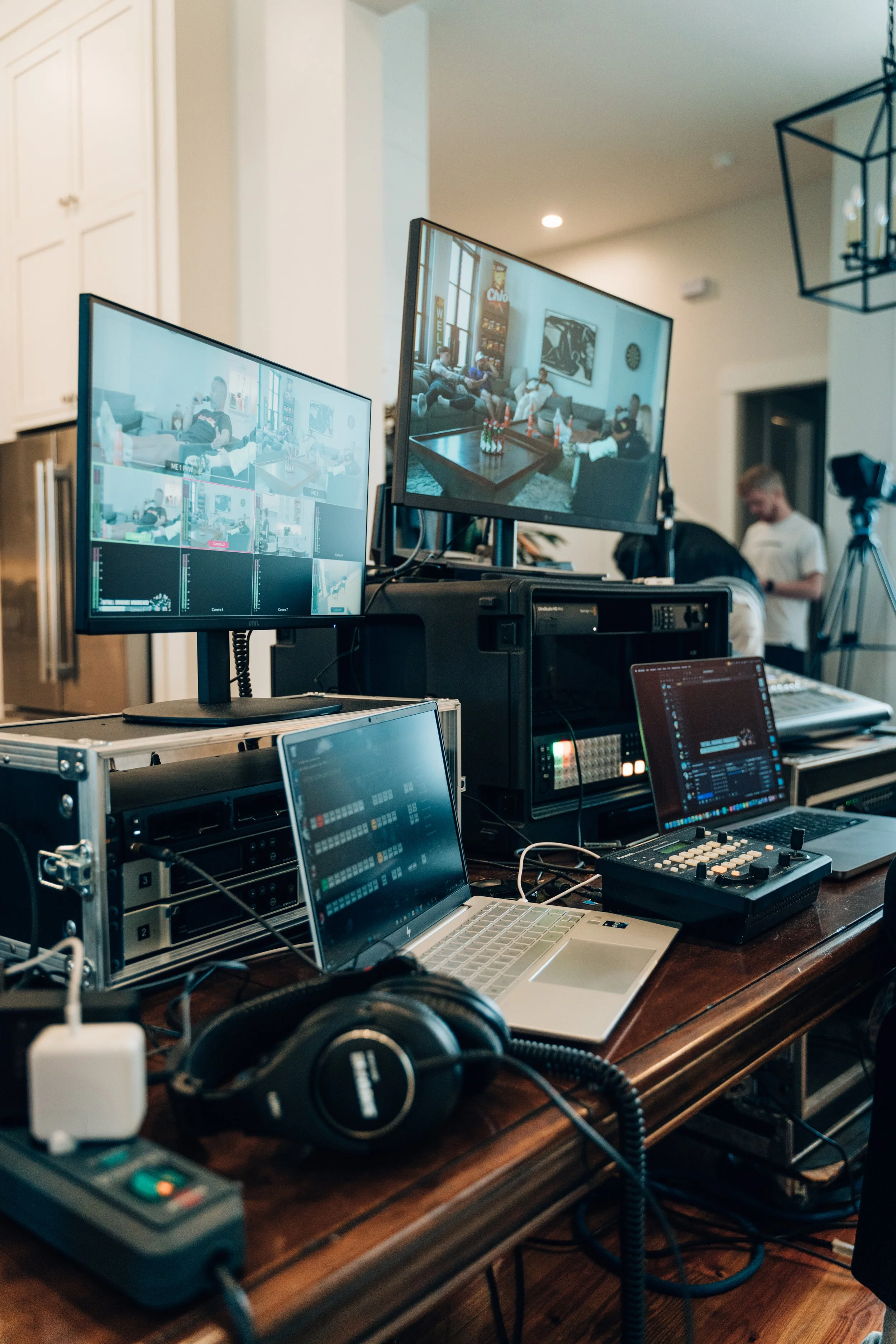 Ein Arbeitsplatz mit mehreren Monitoren, Computer, Audio-Equipment, Kopfhörer, und anderen technischen Geräten in einem Raum.