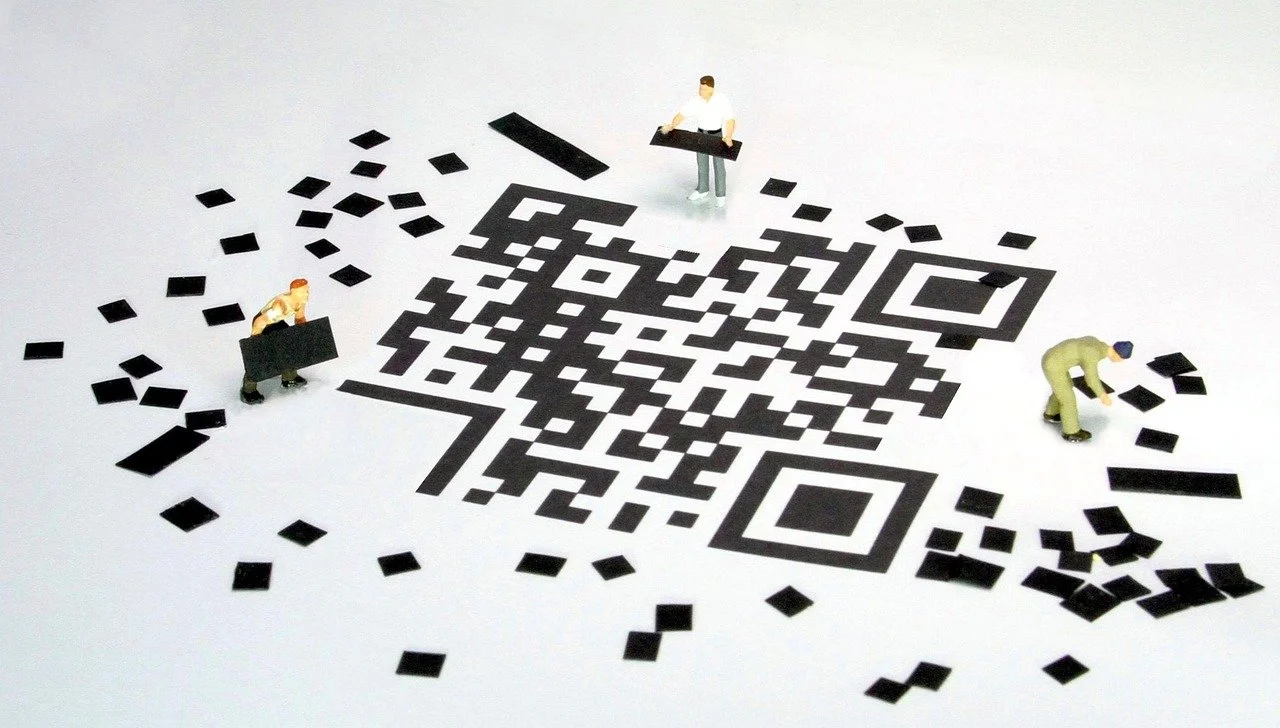 Miniaturas de personas trabajando con un código QR en un fondo blanco., incorporada al sitio del producto Quiero Mi QR de By Enrulada en el ecosistema empresarial Hijas GERENTES.