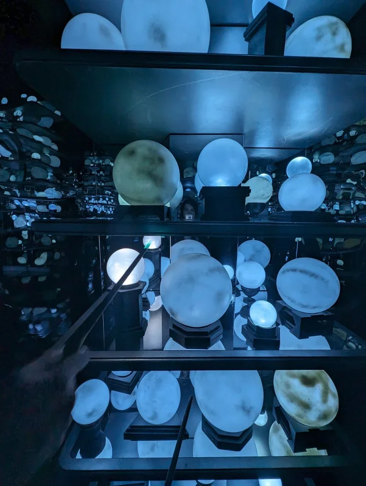 Room with glass globes on shelves and in display cases, illuminated with blue and white lights, creating a calming, futuristic atmosphere.