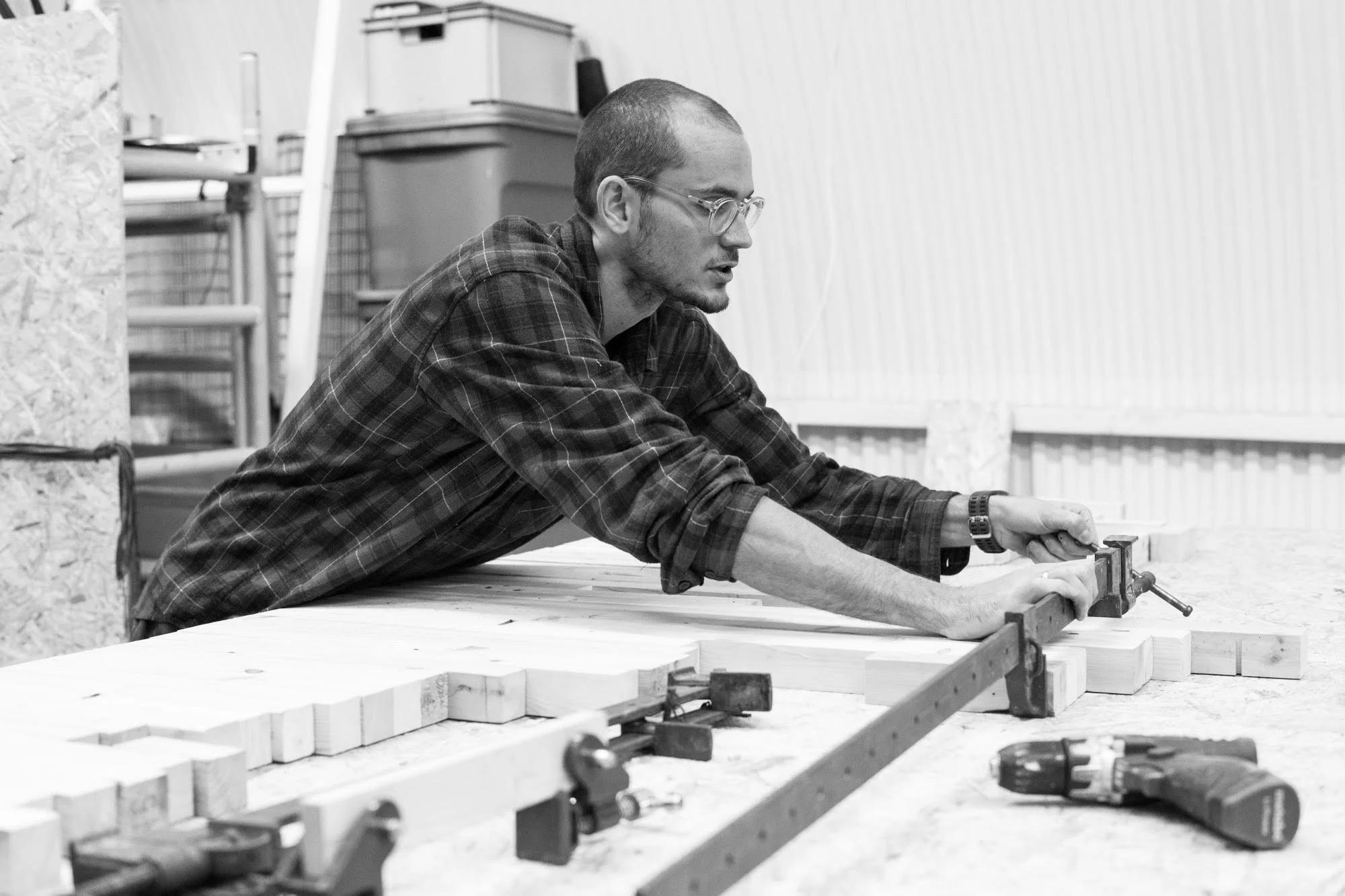 Person working on a maze or puzzle using tools on a table, in black and white.