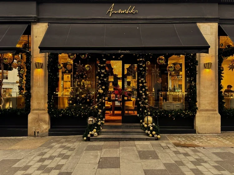 Storefront decorated with Christmas ornaments, garlands, and lights, with a black awning and a sign that says "Amarshka".