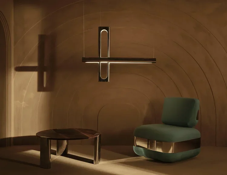 Modern interior with a wooden wall, a unique cross-shaped wall light, a small wooden table, and a green upholstered chair.