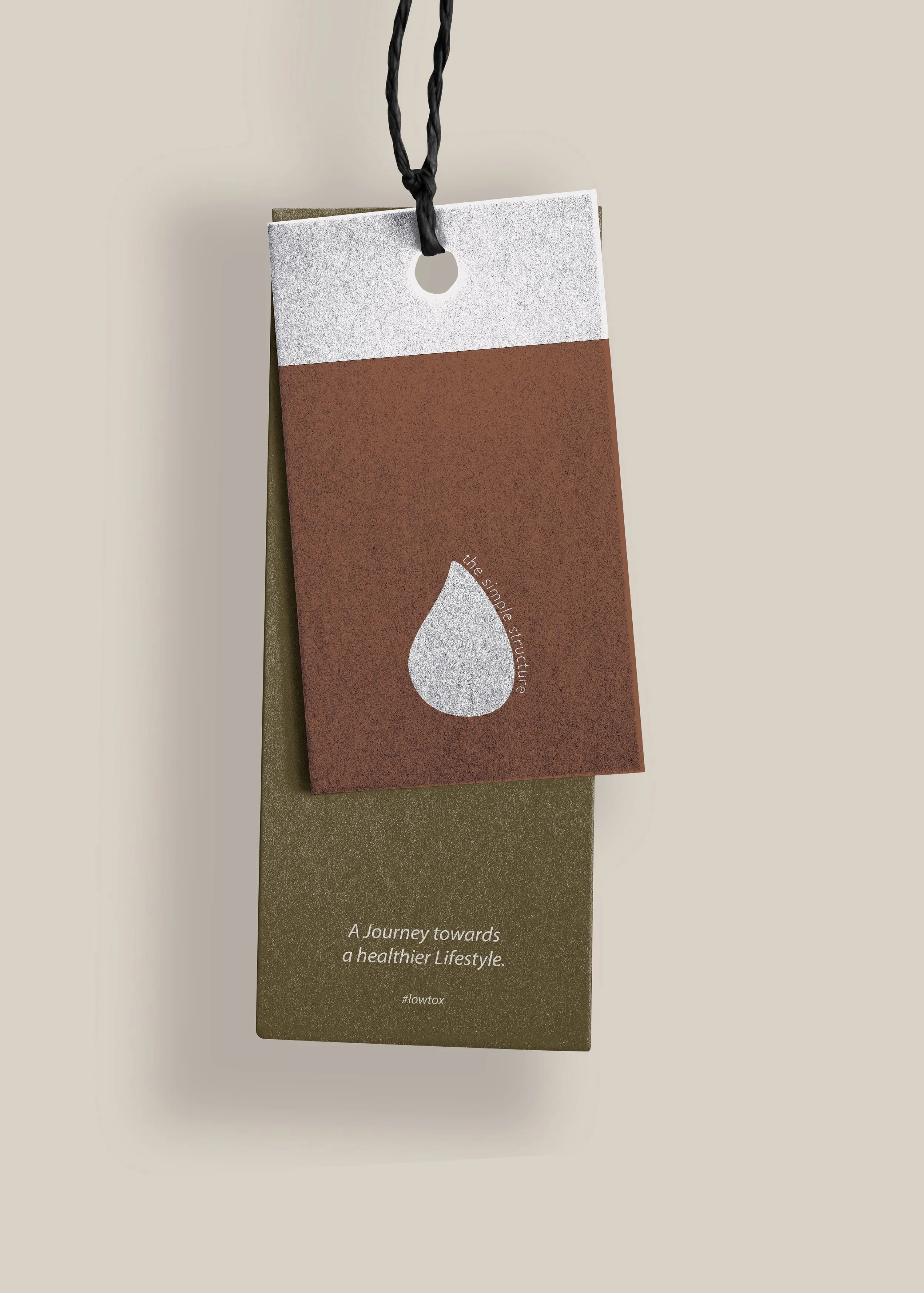 Zwei übereinanderliegende Etiketten mit einem Wassertropfen-Symbol, Text "A Journey towards a healthier Lifestyle" und Hashtag "#lowtox". Beige Hintergrund.