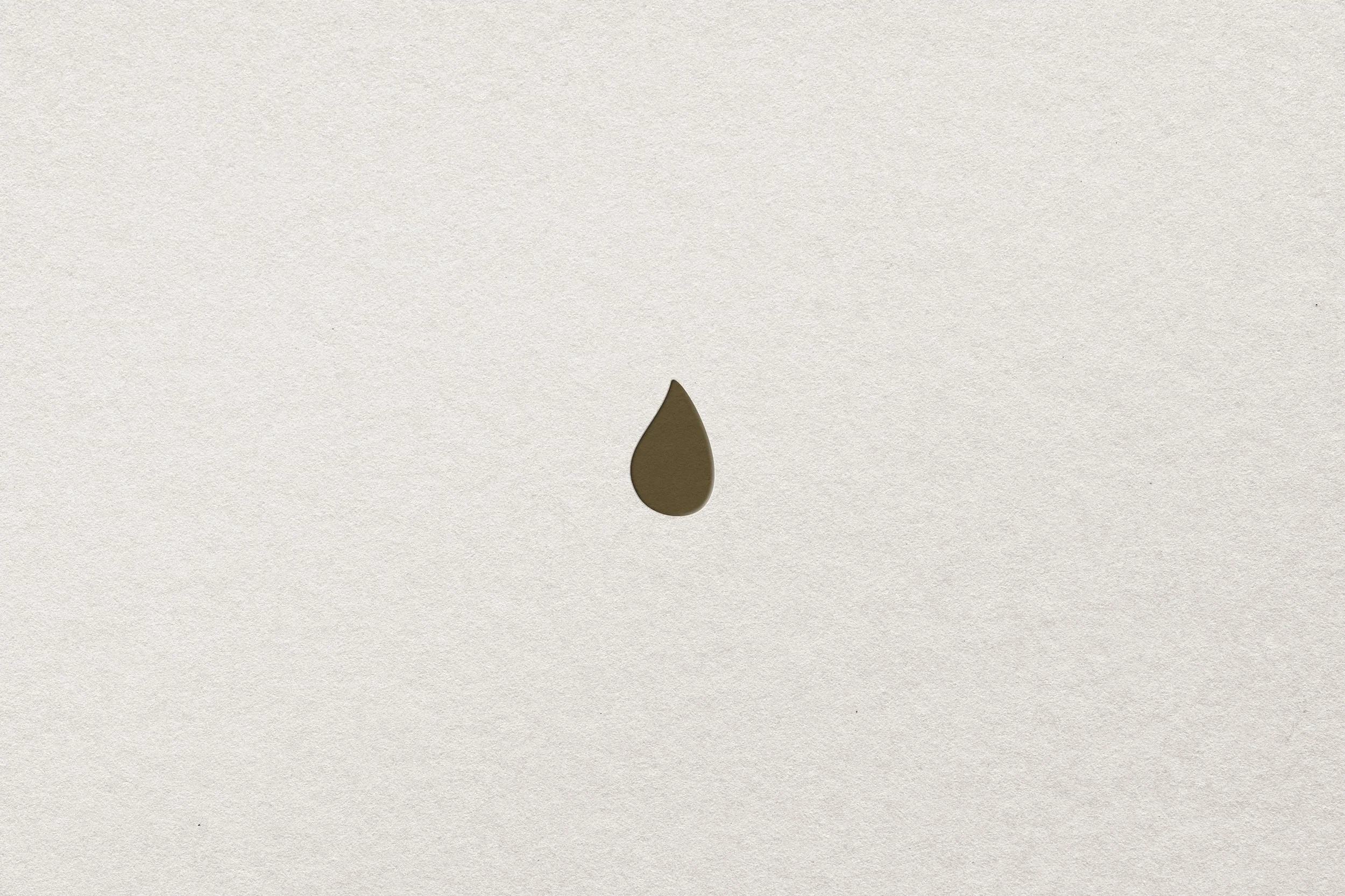Ein brauner Wassertropfen auf einem weißen, strukturierten Hintergrund.