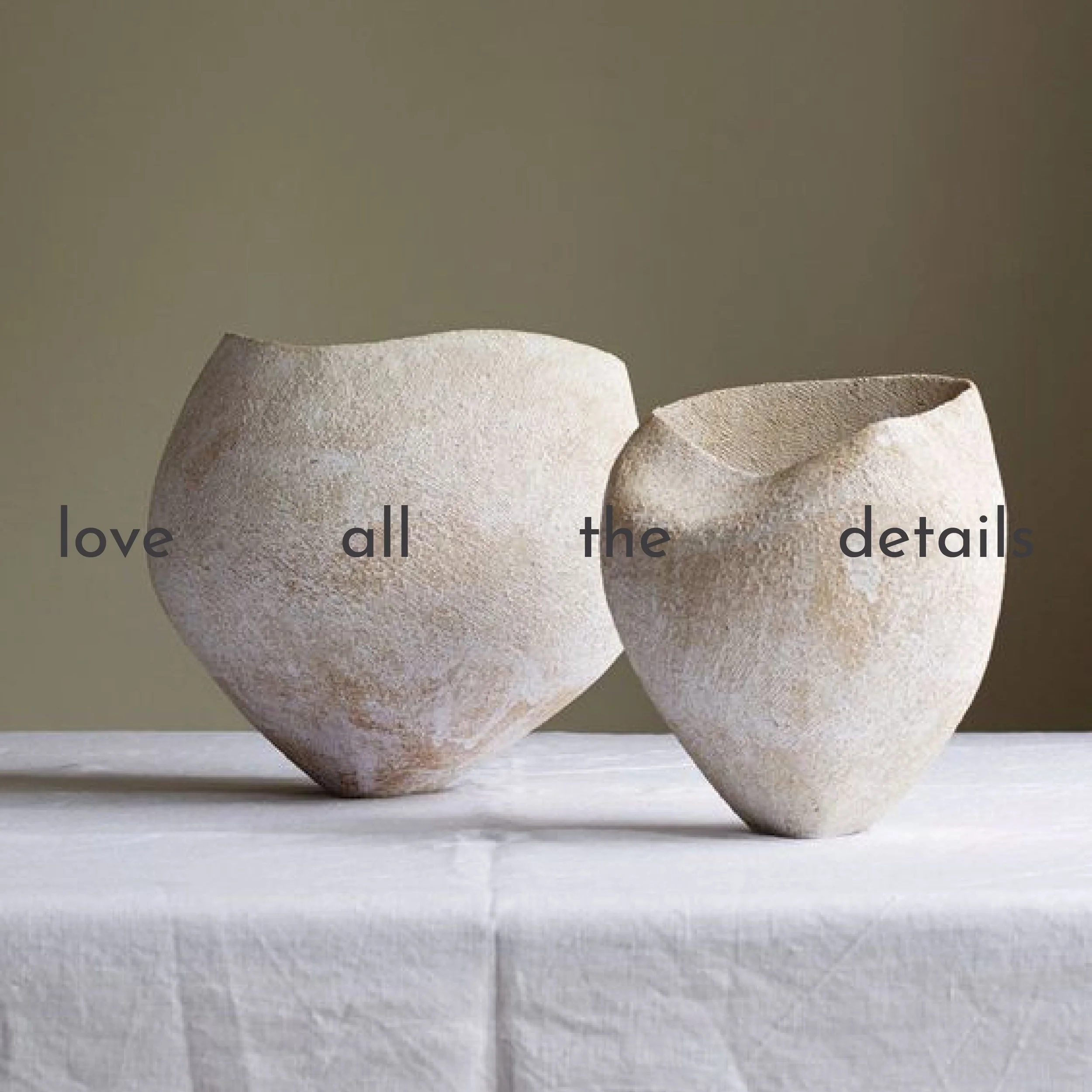 Zwei beige, rauh strukturierte Vasen auf einem weißen Tuch vor einer neutralen Hintergrundwand. Der Text "love all the details" ist auf die Vasen geschrieben.