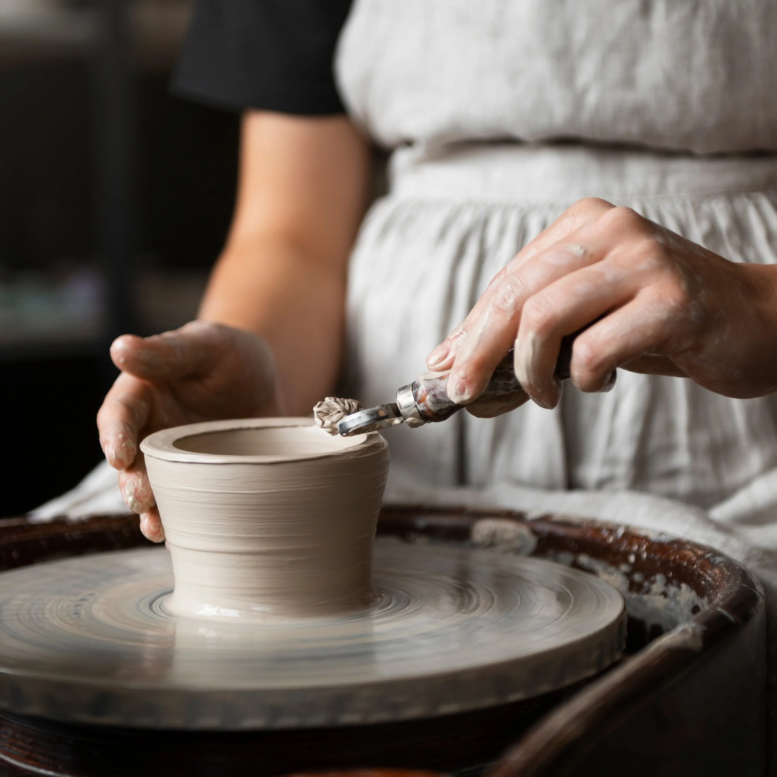 Person, die Ton auf einer Töpferscheibe formt