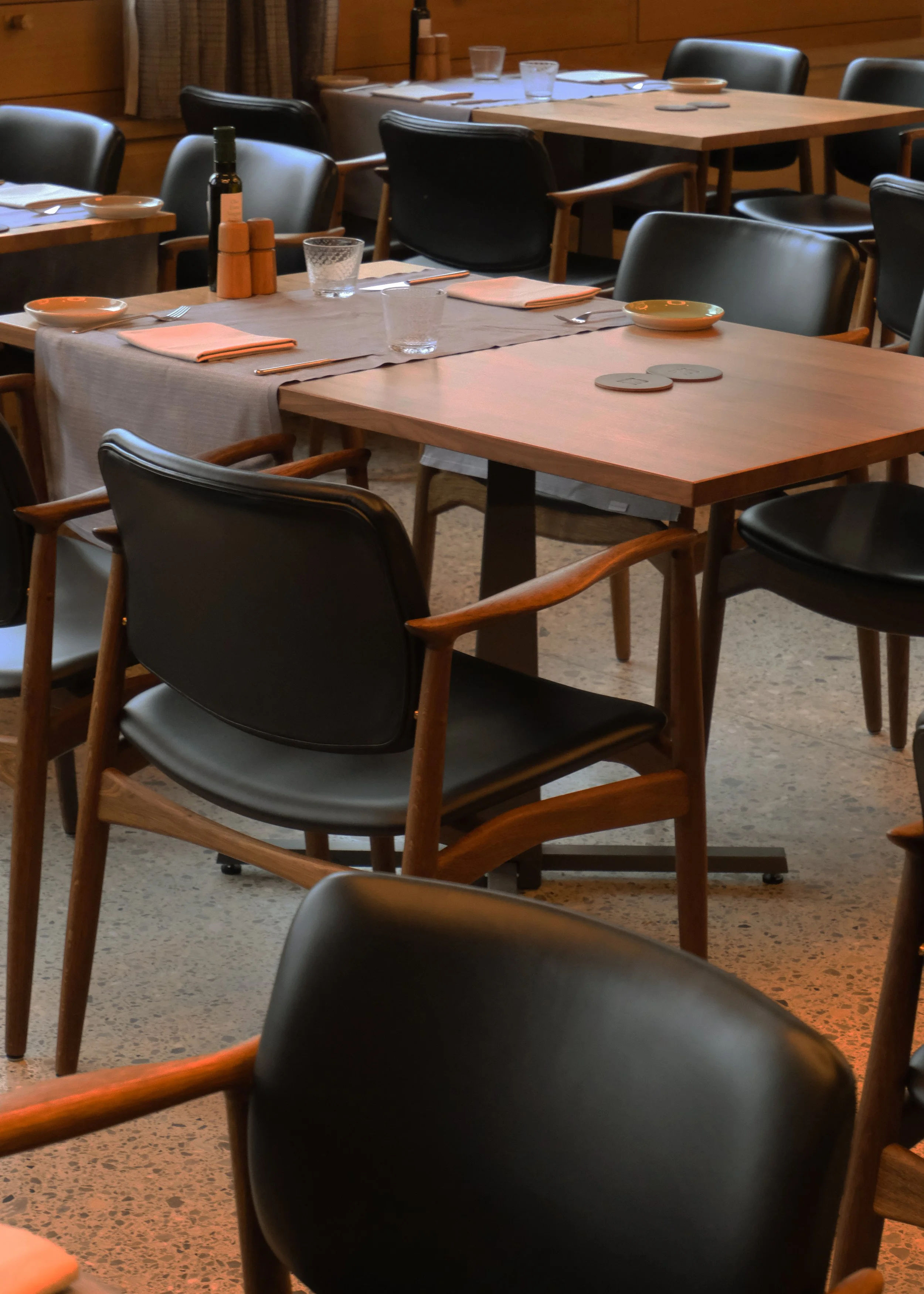 Ein Restaurantraum mit mehreren gedeckten Tischen, schwarzen Stühlen und Gläsern auf den Tischen