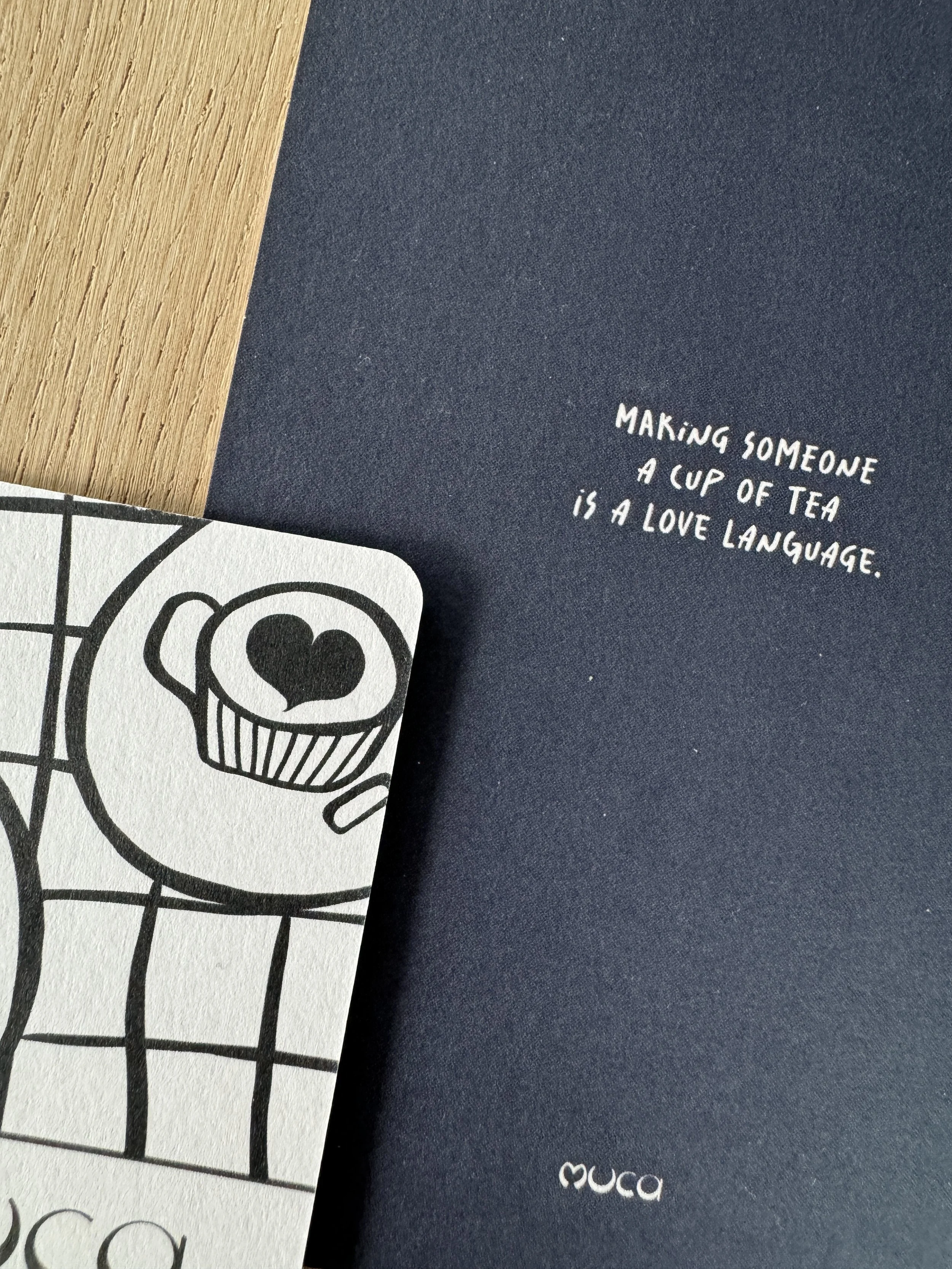 Notizbuch mit weißem Text auf dunkelblauem Hintergrund und eine Karte mit einer stilisierten Zeichnung eines Tieres mit Herz- und Lächelgesicht