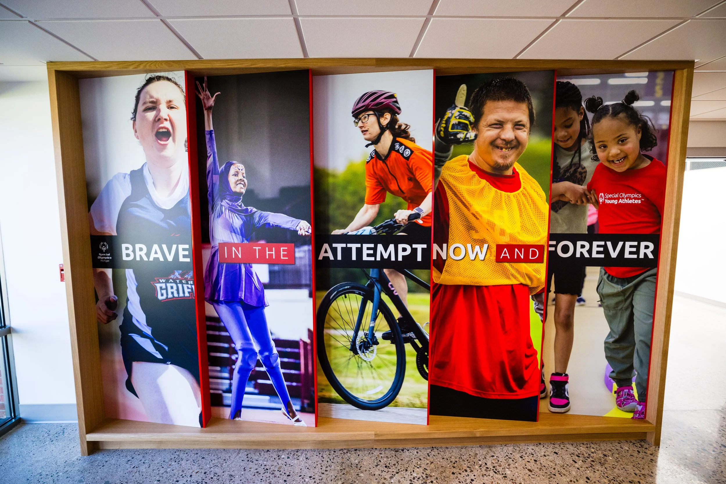 A colorful banner with photos of children and young athletes involved in various sports, and the words 'Brave in the attempt, now and forever.'