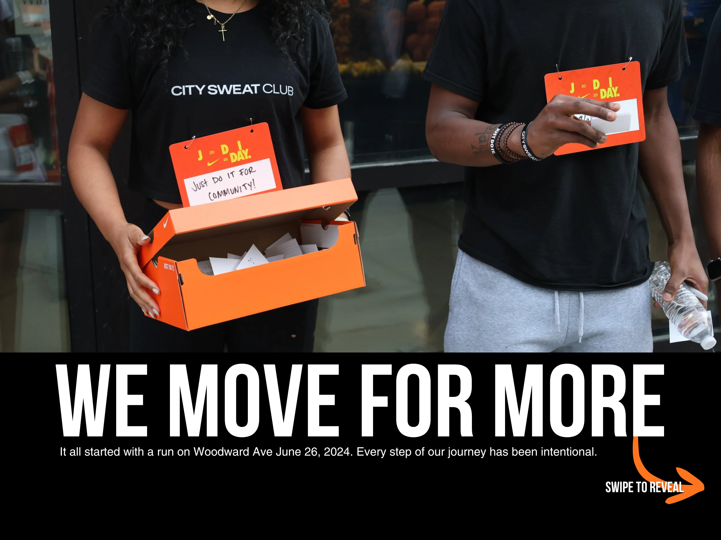 Two people wearing black t-shirts and race bibs participate in a community run event on Woodward Ave, June 26, 2024, holding water bottles and a box of papers.