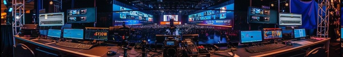 An ultra-wide 6:1 signature footer banner showing a Streaming Inc. technical production riser equipped with redundant encoders and multi-screen monitoring, overlooking a massive corporate audience during a live-streamed keynote event.