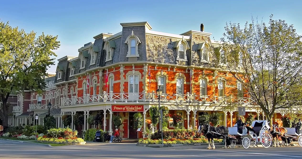 The historic Prince of Wales Hotel in Niagara-on-the-Lake featuring its signature red-brick Victorian architecture and a horse-drawn carriage out front, serving as a premier venue for executive retreats and hybrid corporate events.