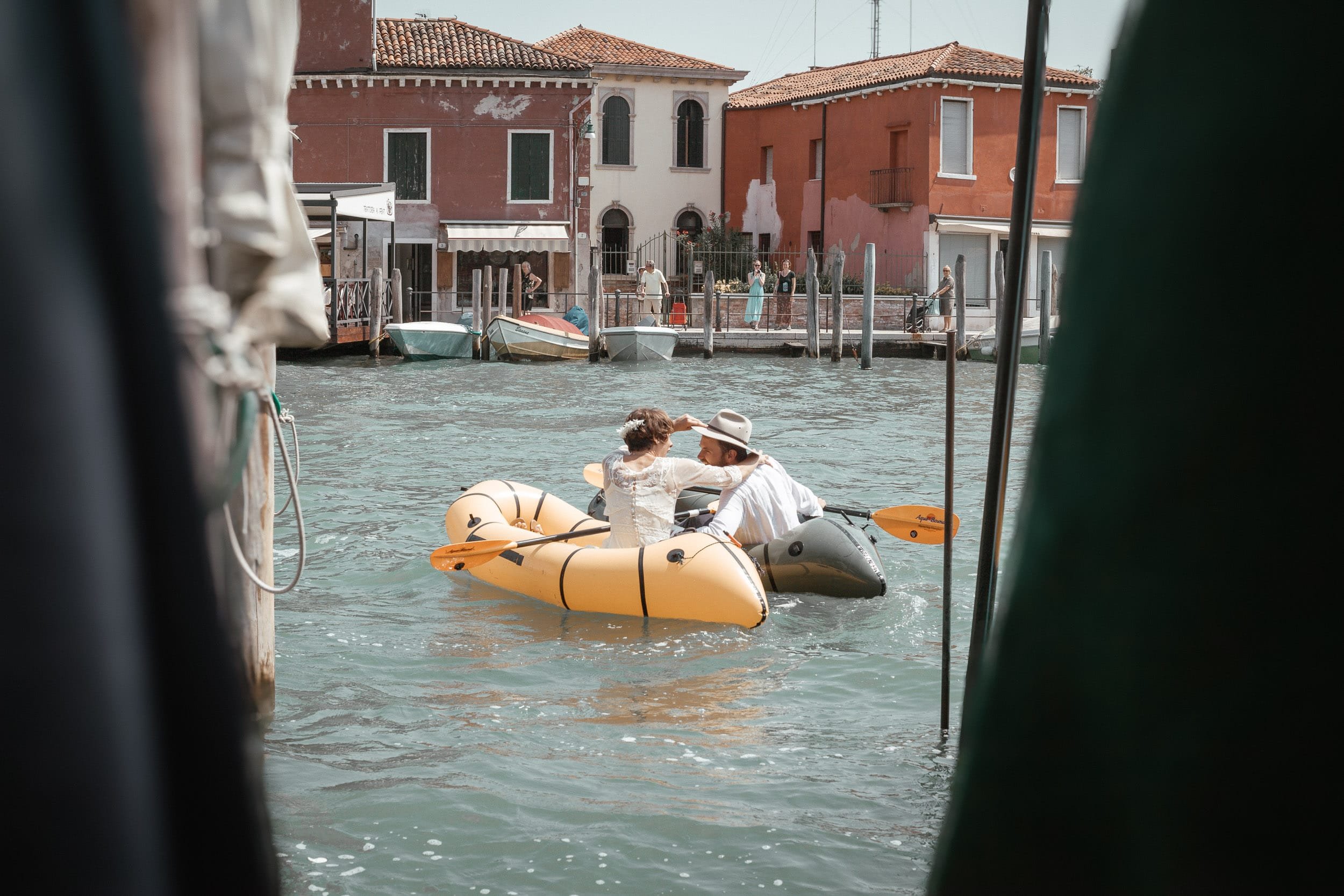 Bride and groom on canoes in Venice, Italy about to go in for a kiss.