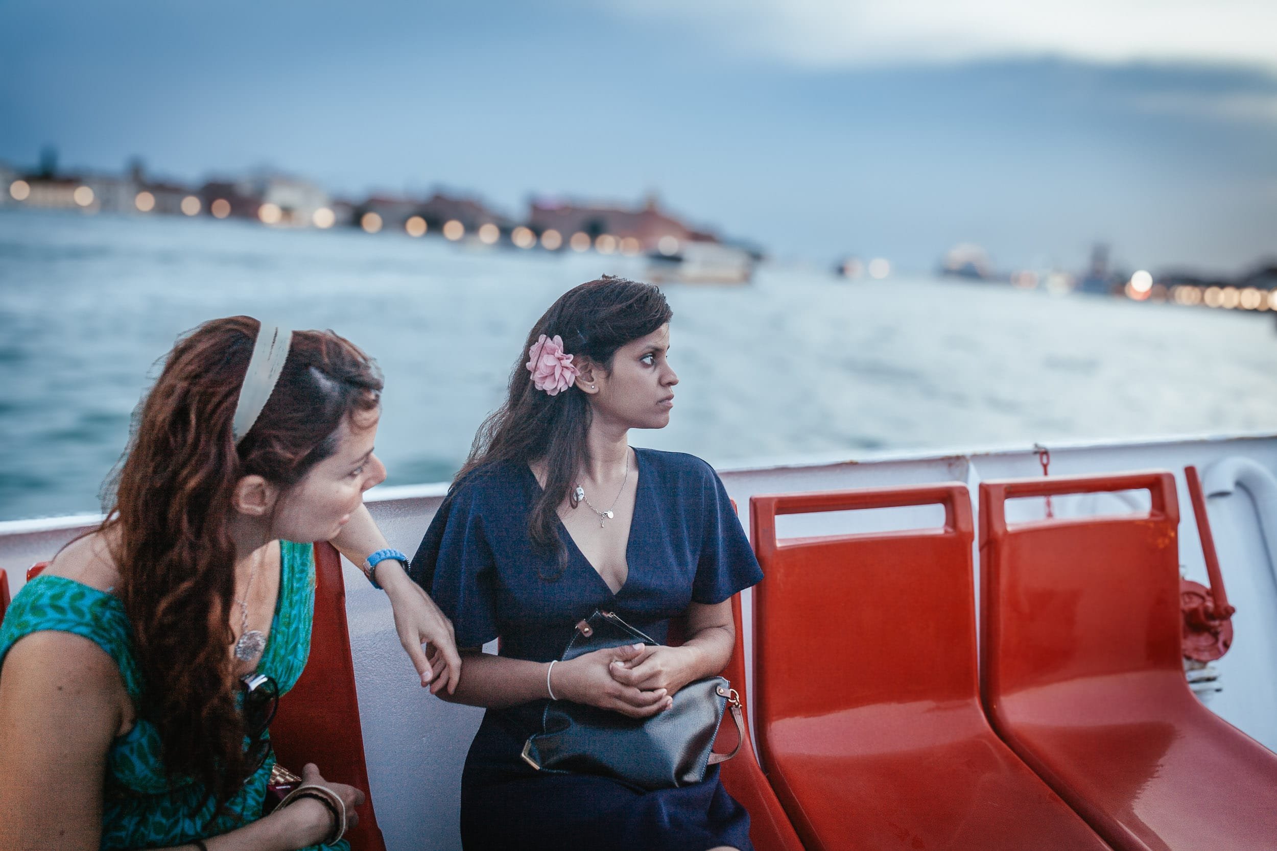Two women and wedding guests enjoy the scenery while on a boat ride in Venice Italy.
