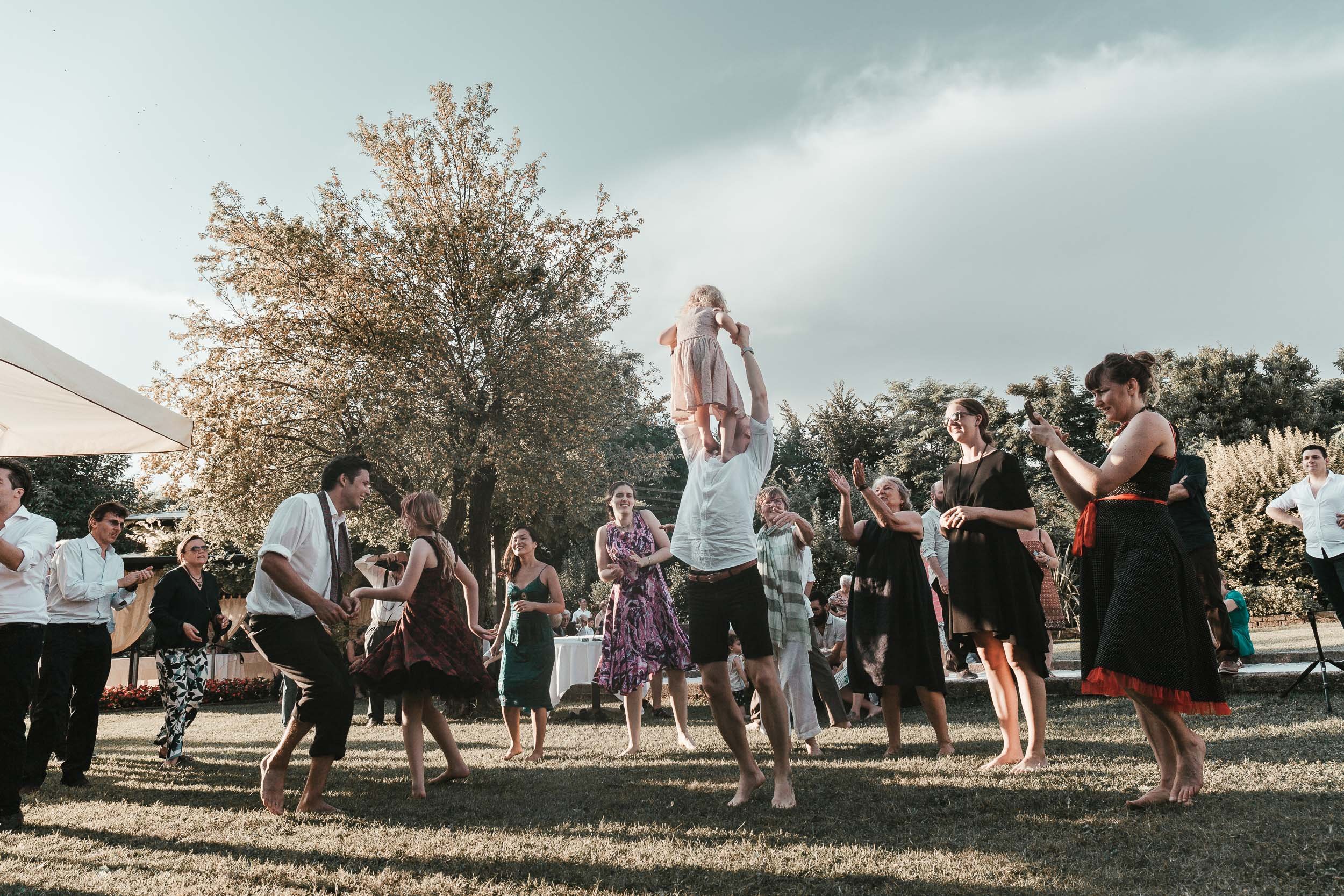 A small girl is thrown into the air as wedding guests dance at the wedding party