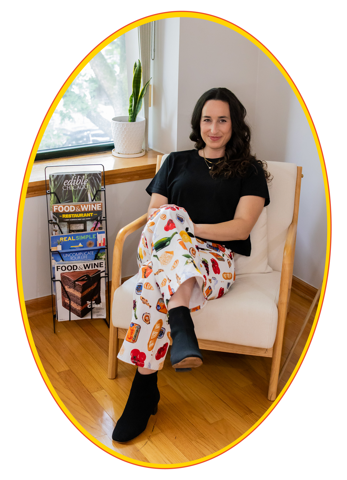 Rachel Becker, founder of Kitchen Sink Communications, in patterned pants seated casually in a bright, plant-filled interior space, conveying approachable creative energy