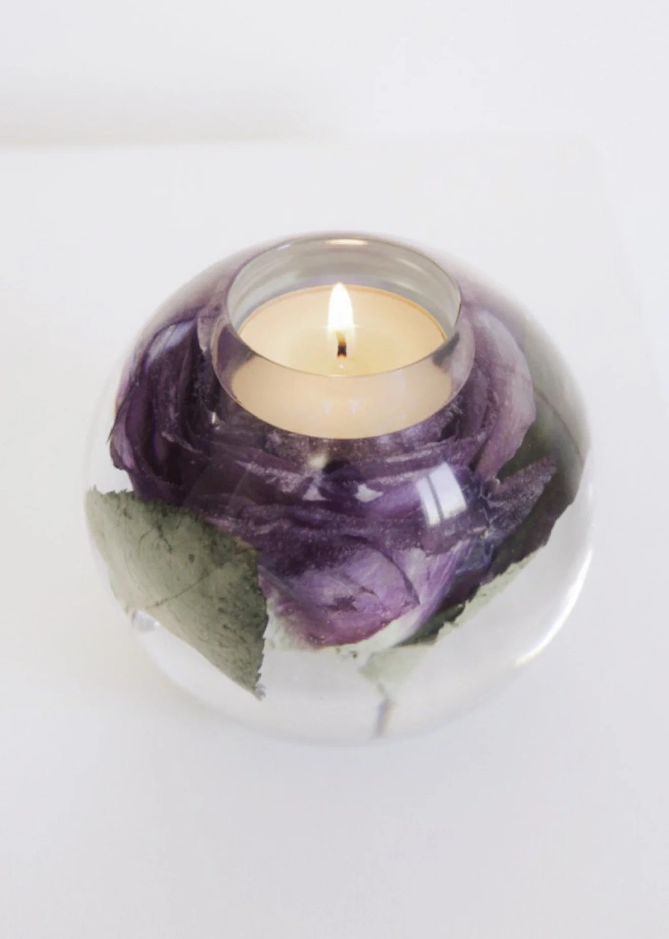 Tea light holder with wedding bouquet preserved in them and a tea light inside lit 