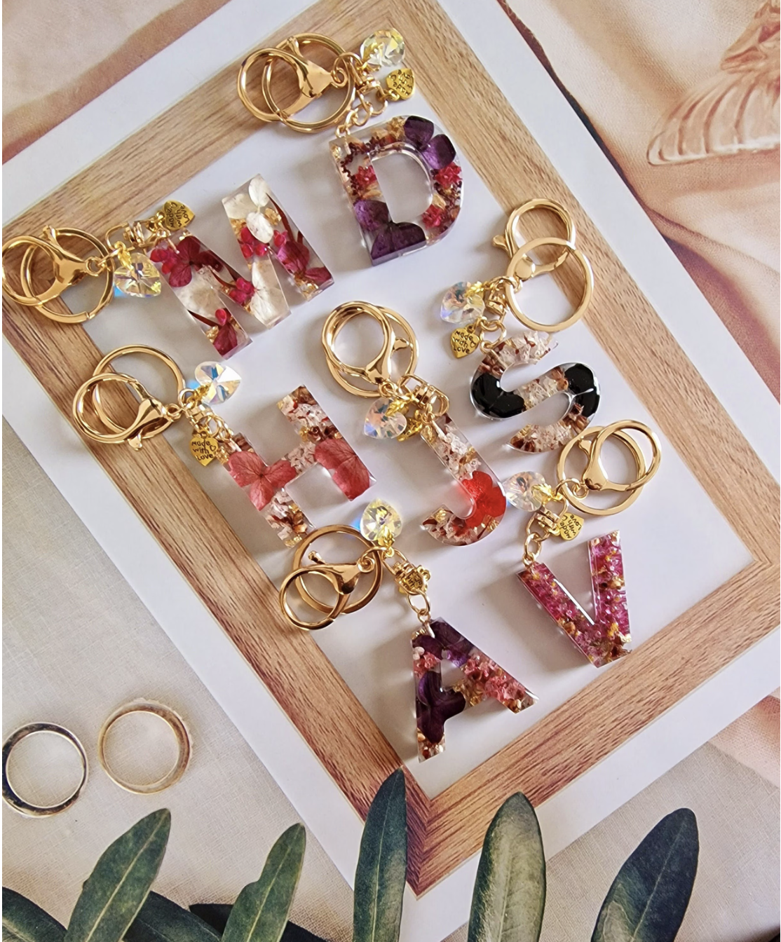 letter keychains in a wooden frame with flowers inside with gold chains