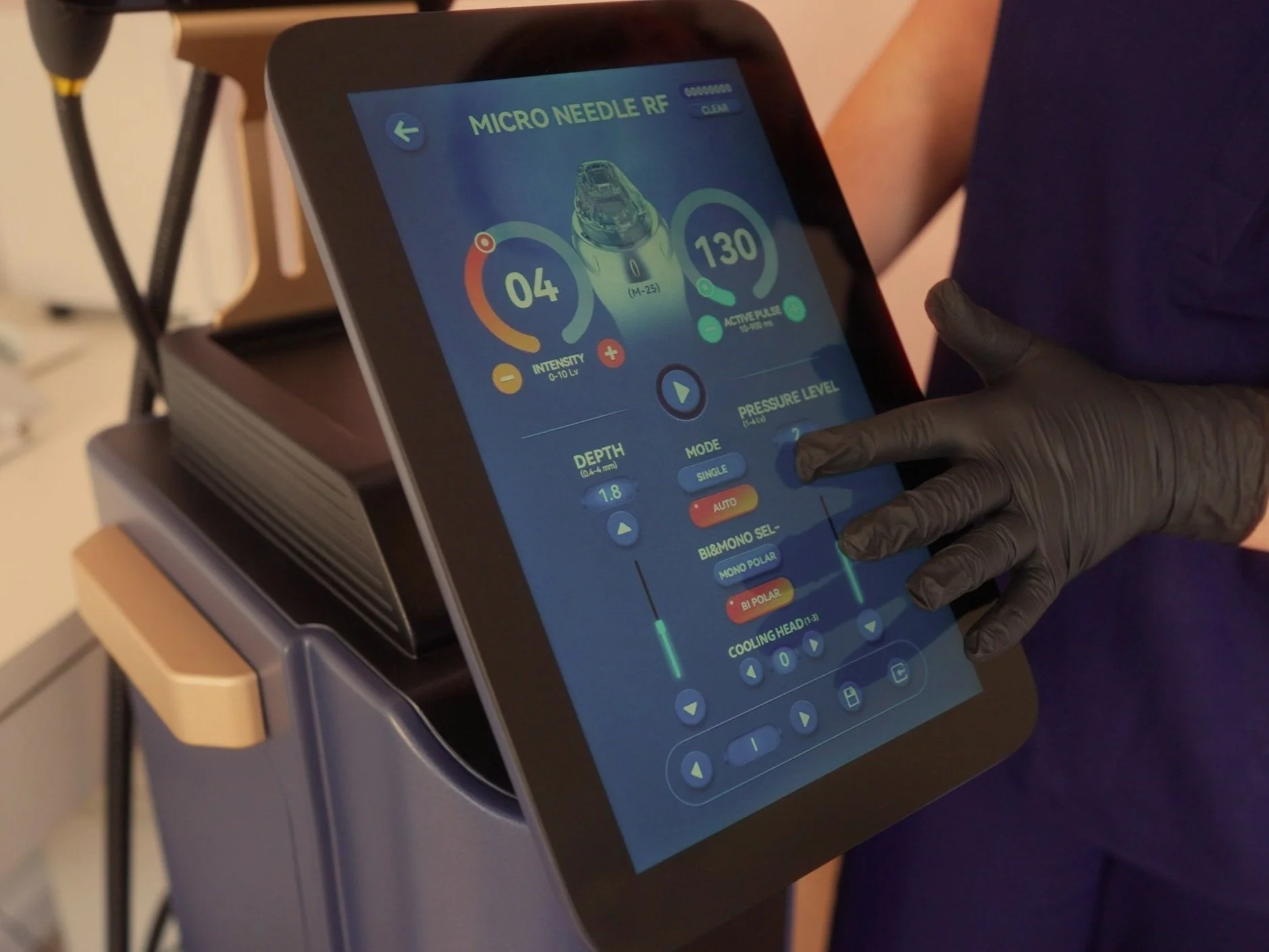 Touchscreen medical device displaying settings for micro needle RF, including oxygen levels, pressure, depth, mode, and cooling head controls, with a person wearing black gloves operating it.