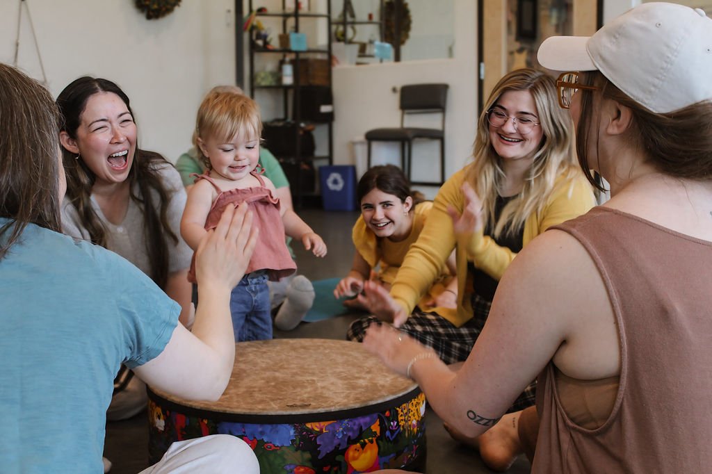 Families laughing and playing the drum in Music Together class