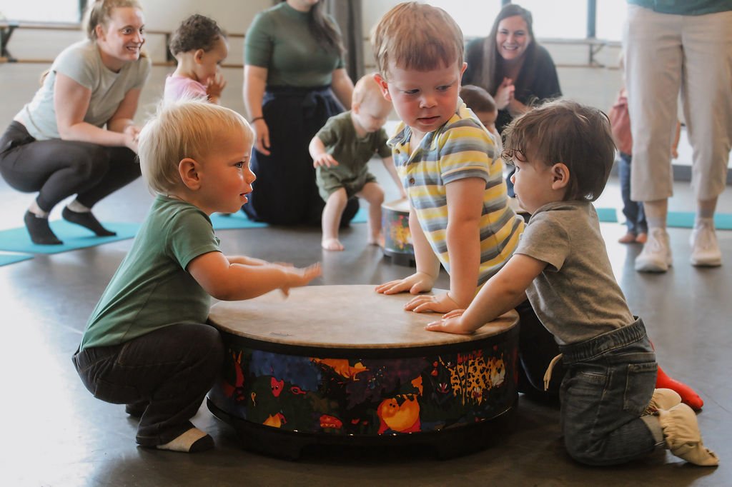 toddlers and preschooler in music class with drum