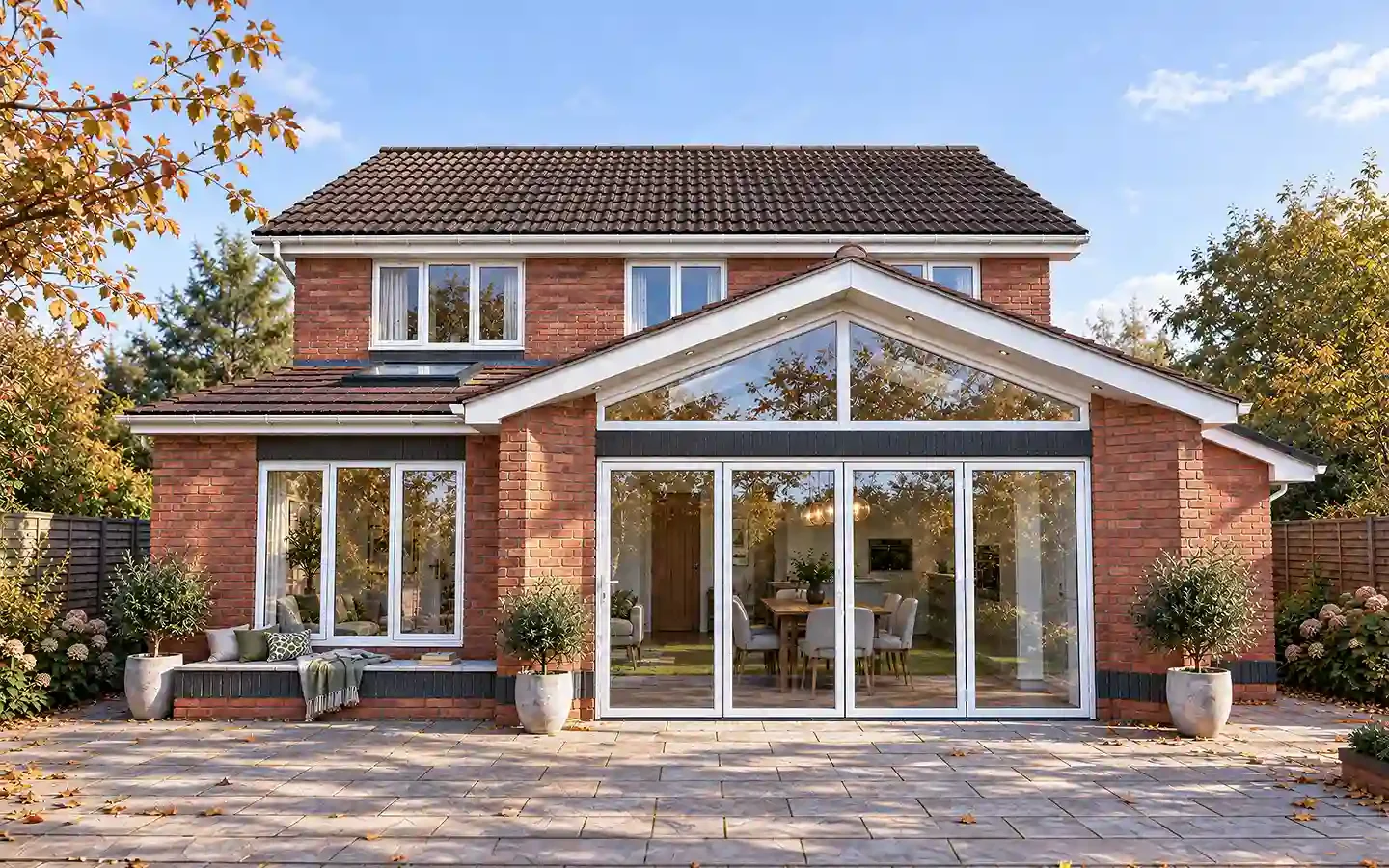 Rear garden view of a single-storey extension in Solihull, with a glazed gable, bifold doors, a triangular feature window and a mono-pitched side section.