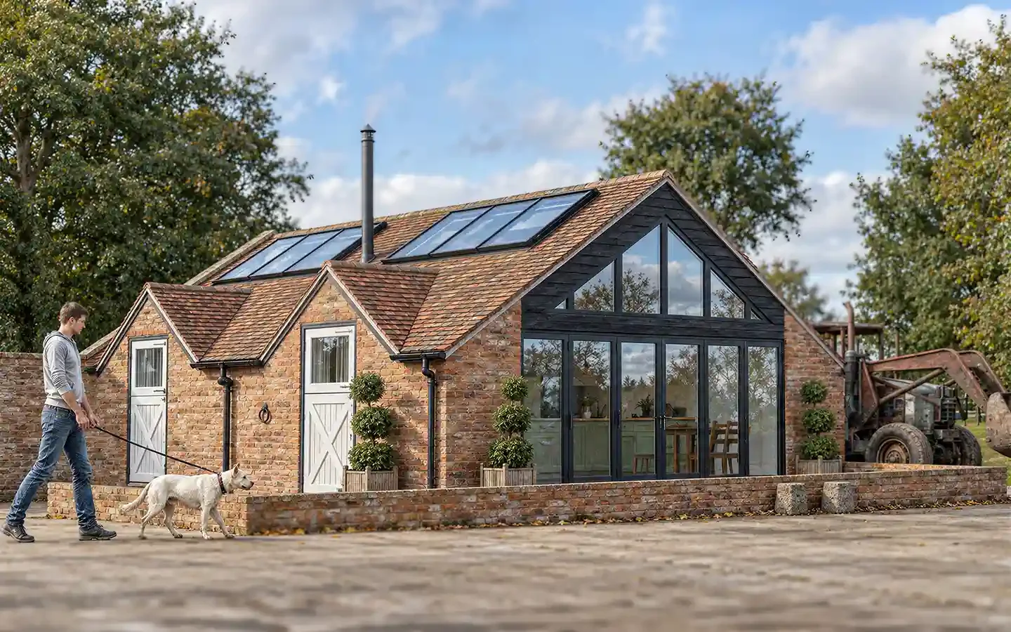 Proposed farm outbuilding conversion to Airbnb accommodation in Warwickshire, viewed from the farmyard, with brick walls, glazed gable, dark timber cladding and rooflights.