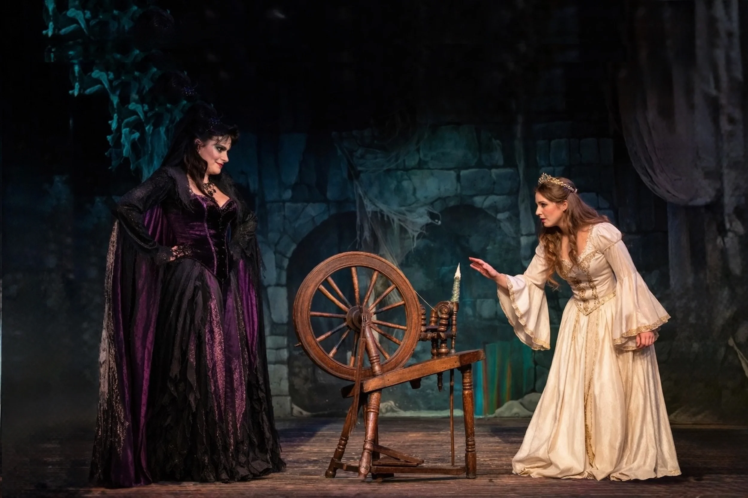 Aurora and Carabosse with the spinning wheel in a Sleeping Beauty pantomime production photo