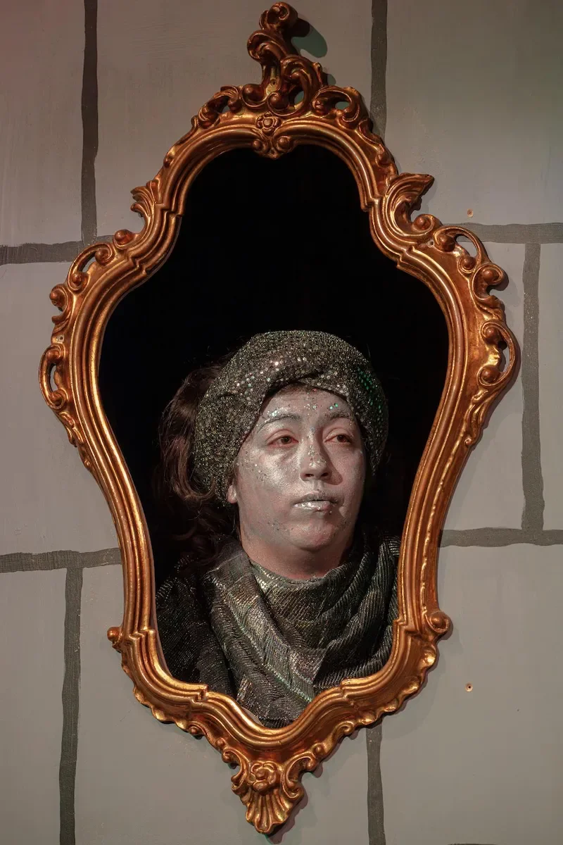 The Magic Mirror appears in a gilded frame with a silver-painted face, in a production of the Snow White pantomime script.