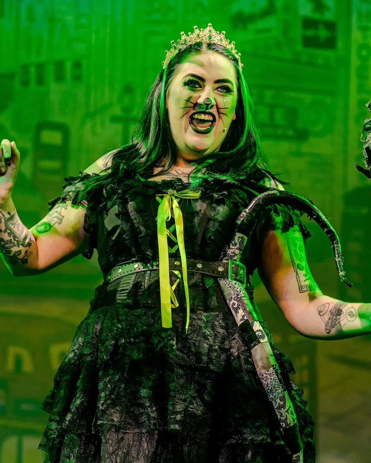Queen Rat, wearing black and green laughing manically