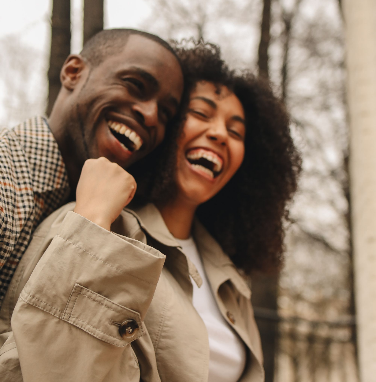 Two smiling people, a man and a woman, outdoors in a wooded area, celebrating with a fist pump.