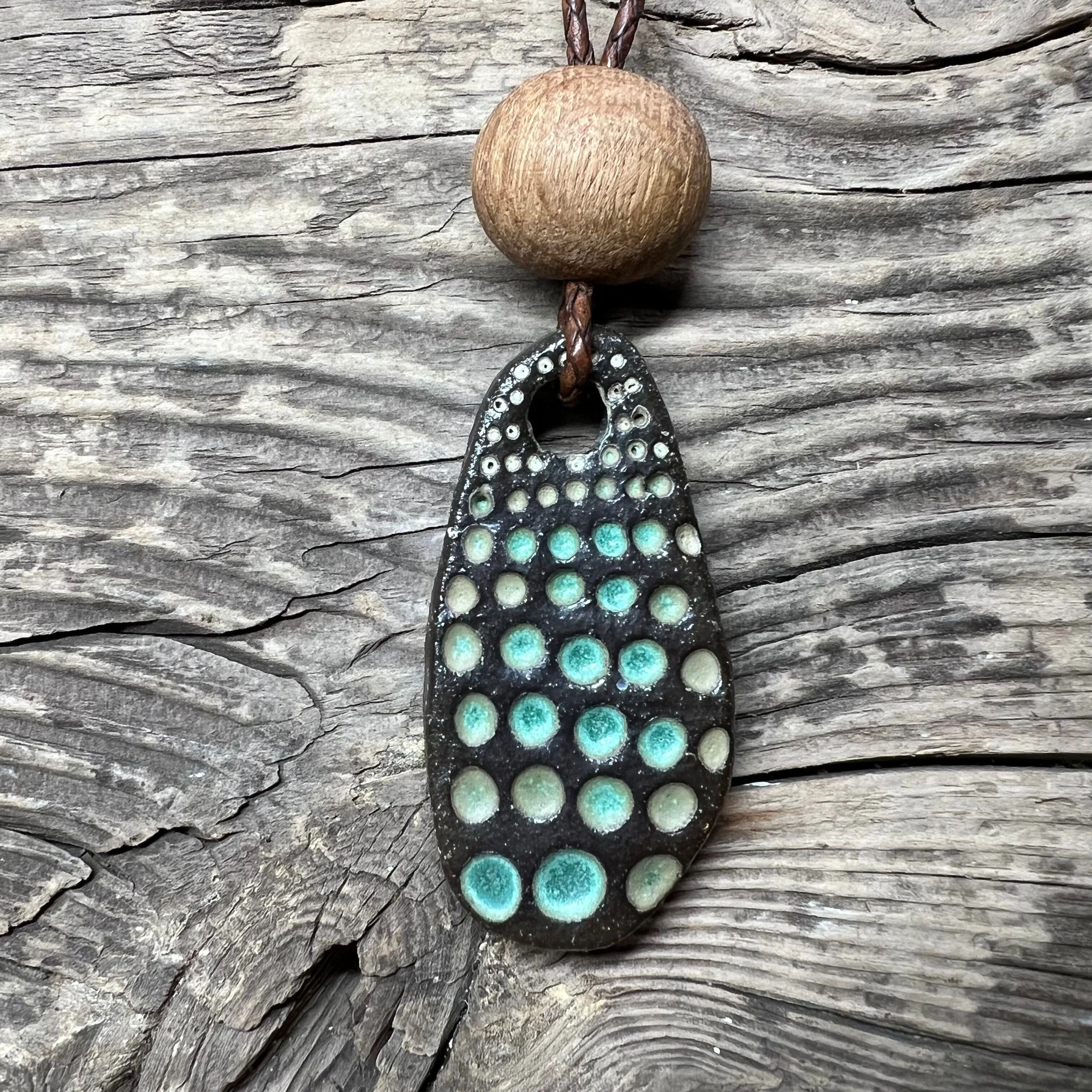 a dark stoneware clay pendant, wooden bead with a green glaze inlay