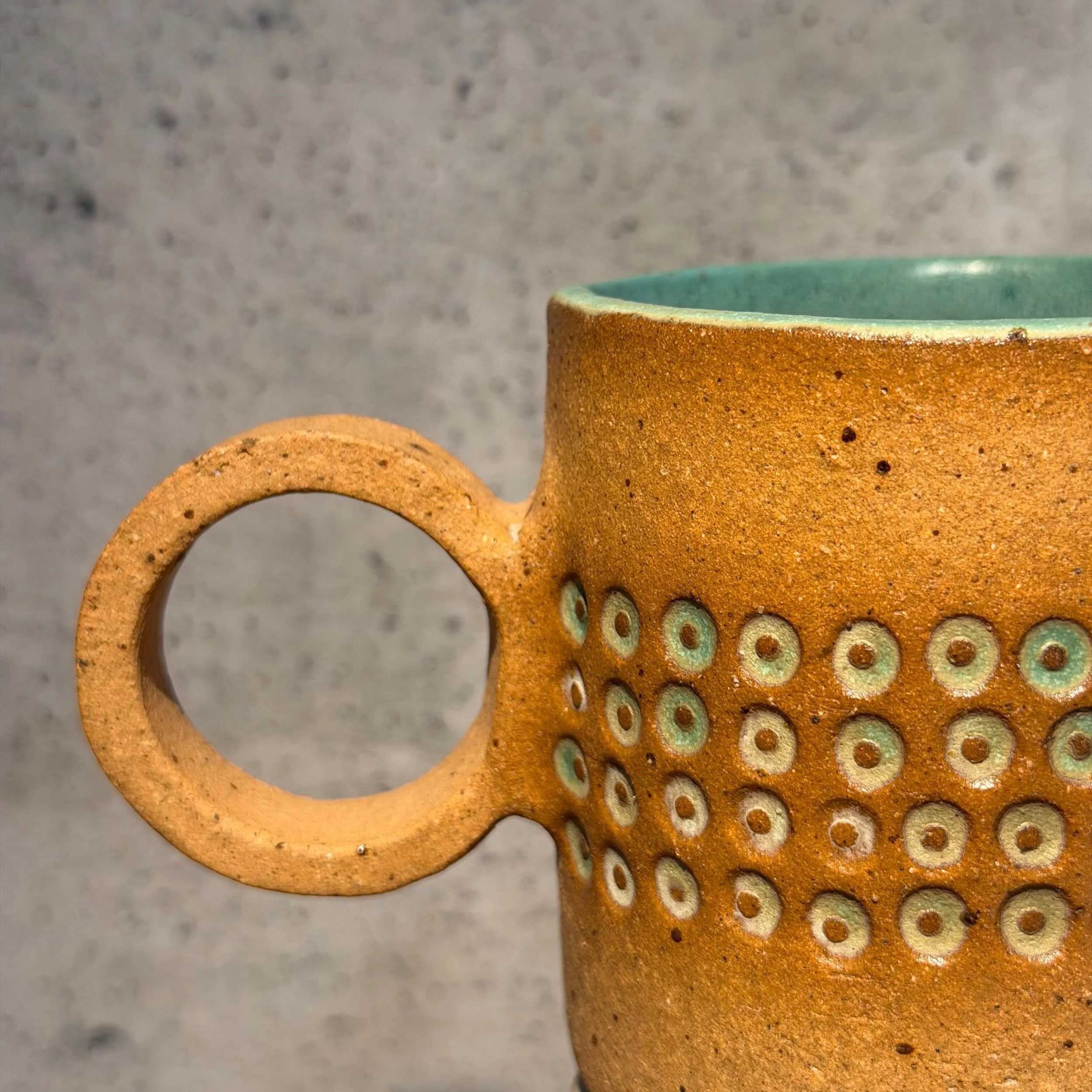 handcrafted cup, made from speckled stoneware clay.   Finished in a beautiful satin patina green glaze on the inside, inlaid on the outside with a comfortable circular handle.