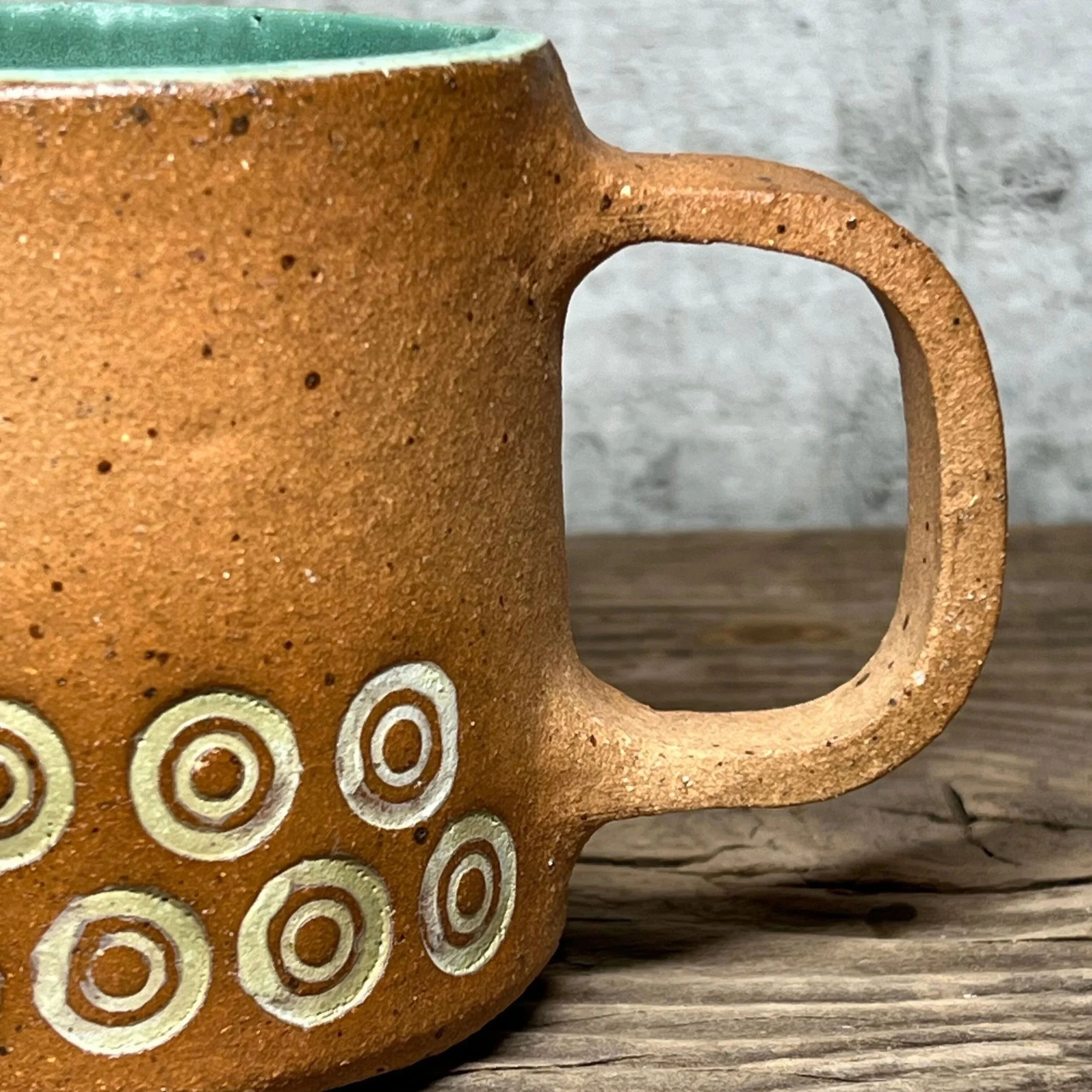 handcrafted cup, made from speckled stoneware clay.   Finished in a beautiful green glaze on the inside with an inlay of circles on the outside.