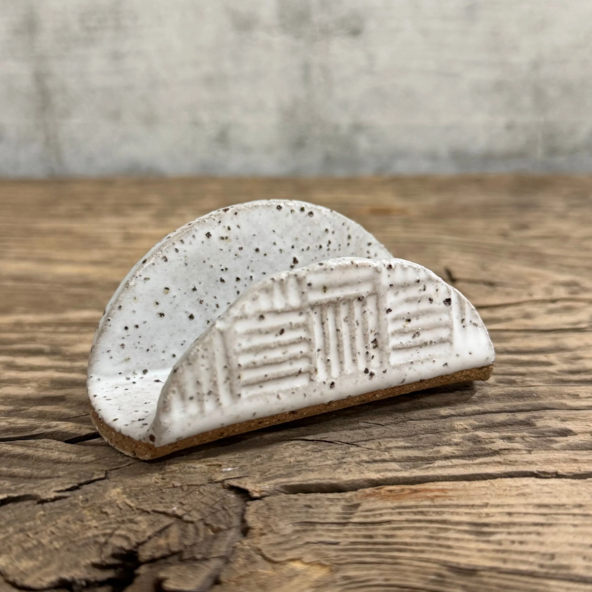 A textured handmade ceramic business card holder with a matte white finish