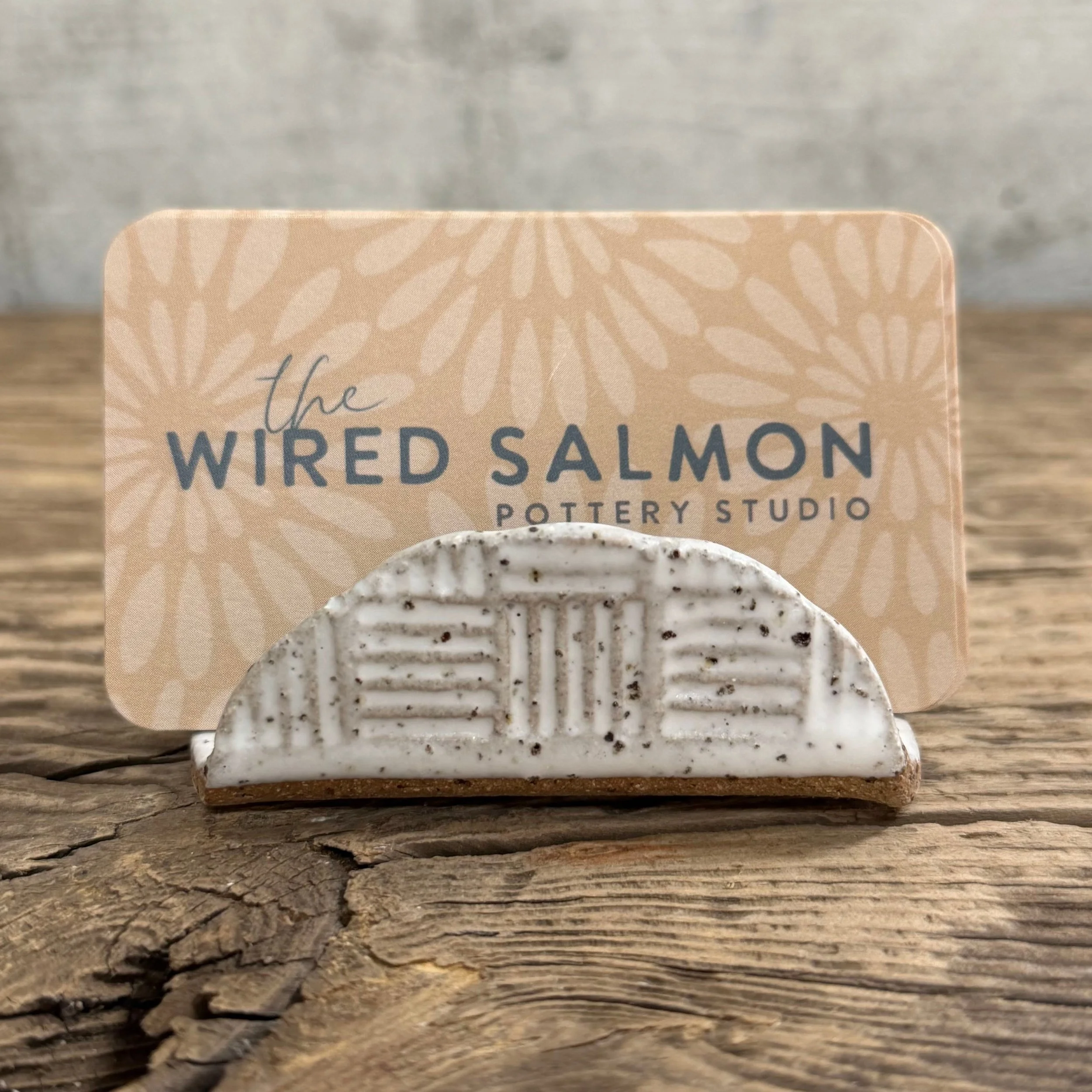 A textured handmade ceramic business card holder with a matte white finish
