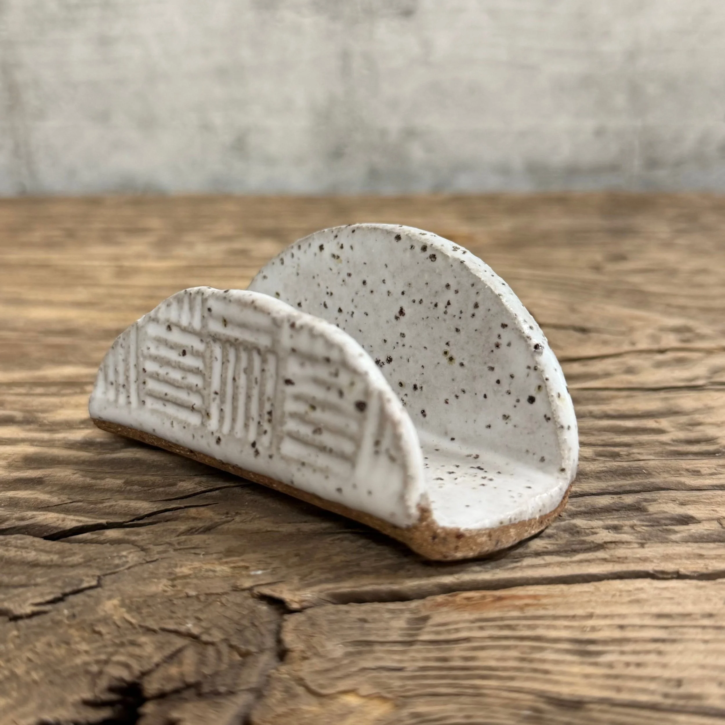 A textured handmade ceramic business card holder with a matte white finish