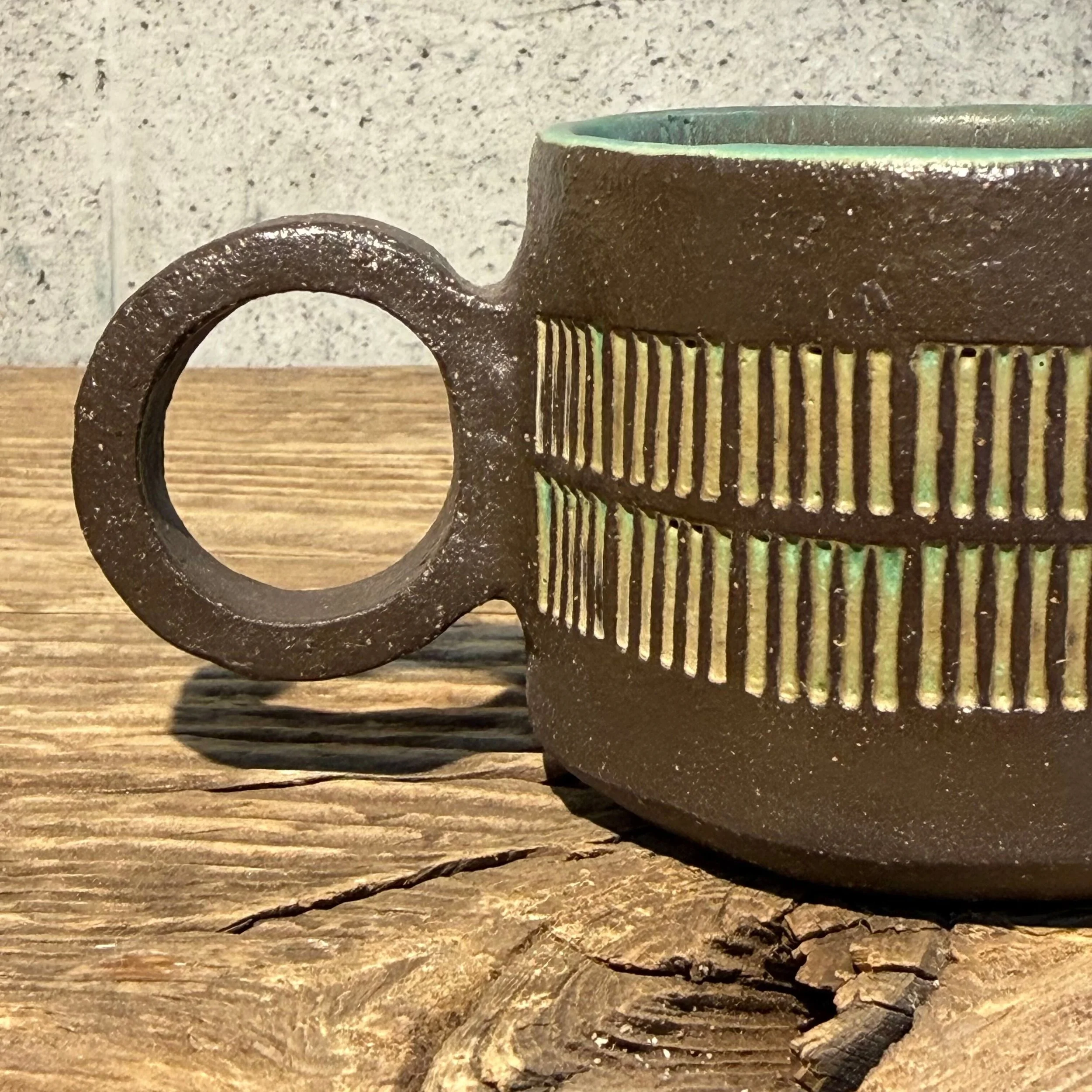 dark stoneware clay, finished in a beautiful mottled green glaze on the inside and inlaid on the outside