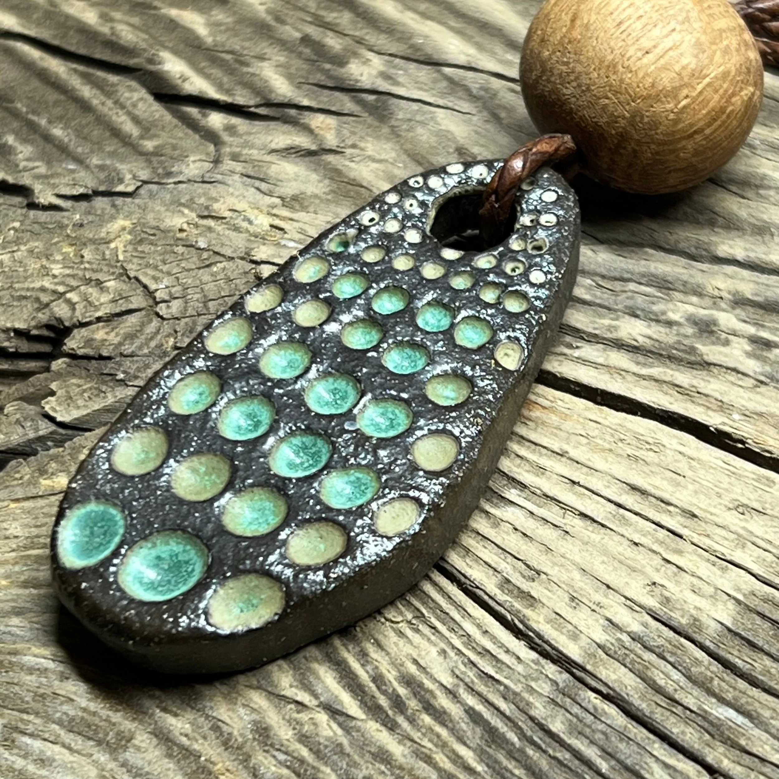 a dark stoneware clay pendant, wooden bead with a green glaze inlay