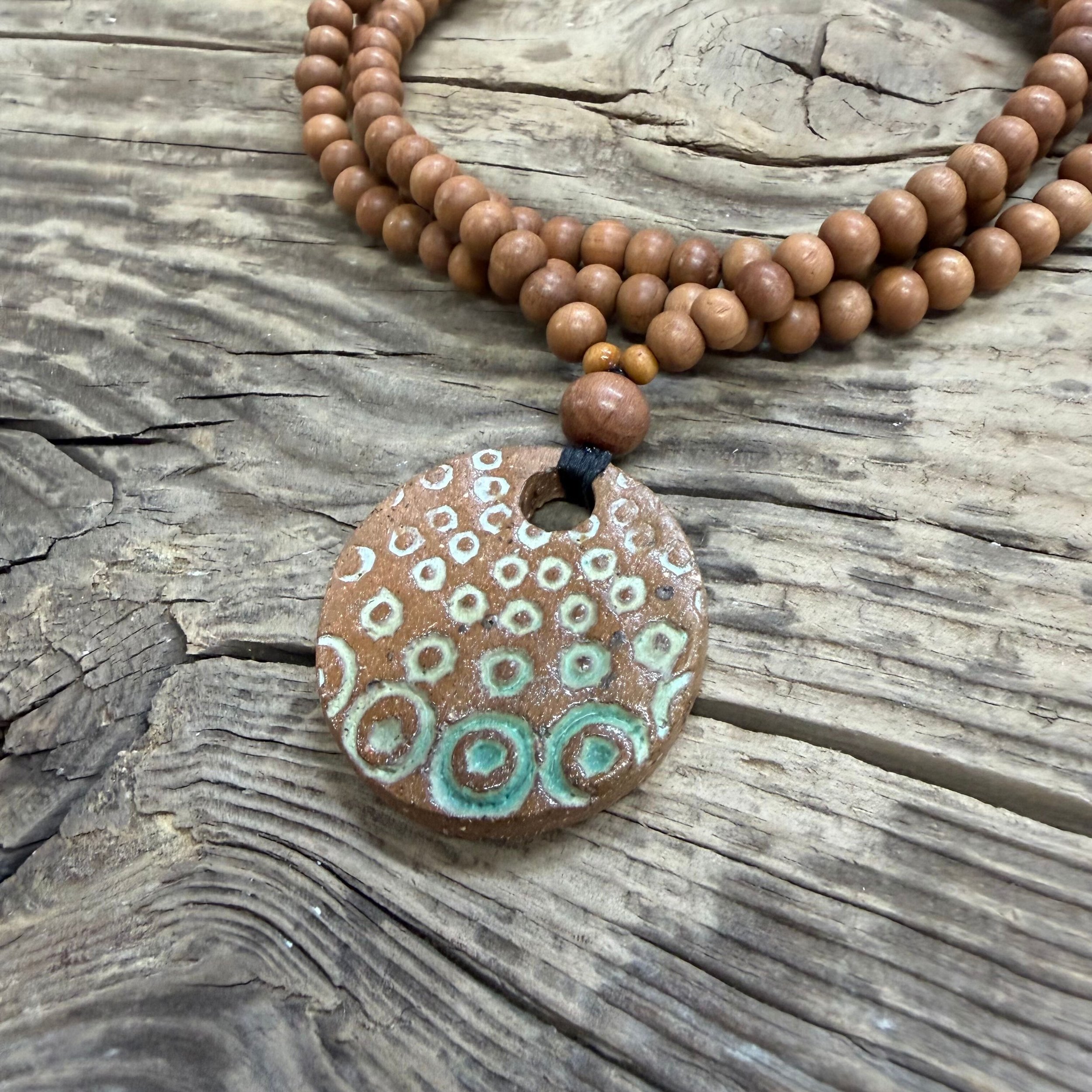 textured stoneware clay pendant with and is finished with with a green glaze inlay.