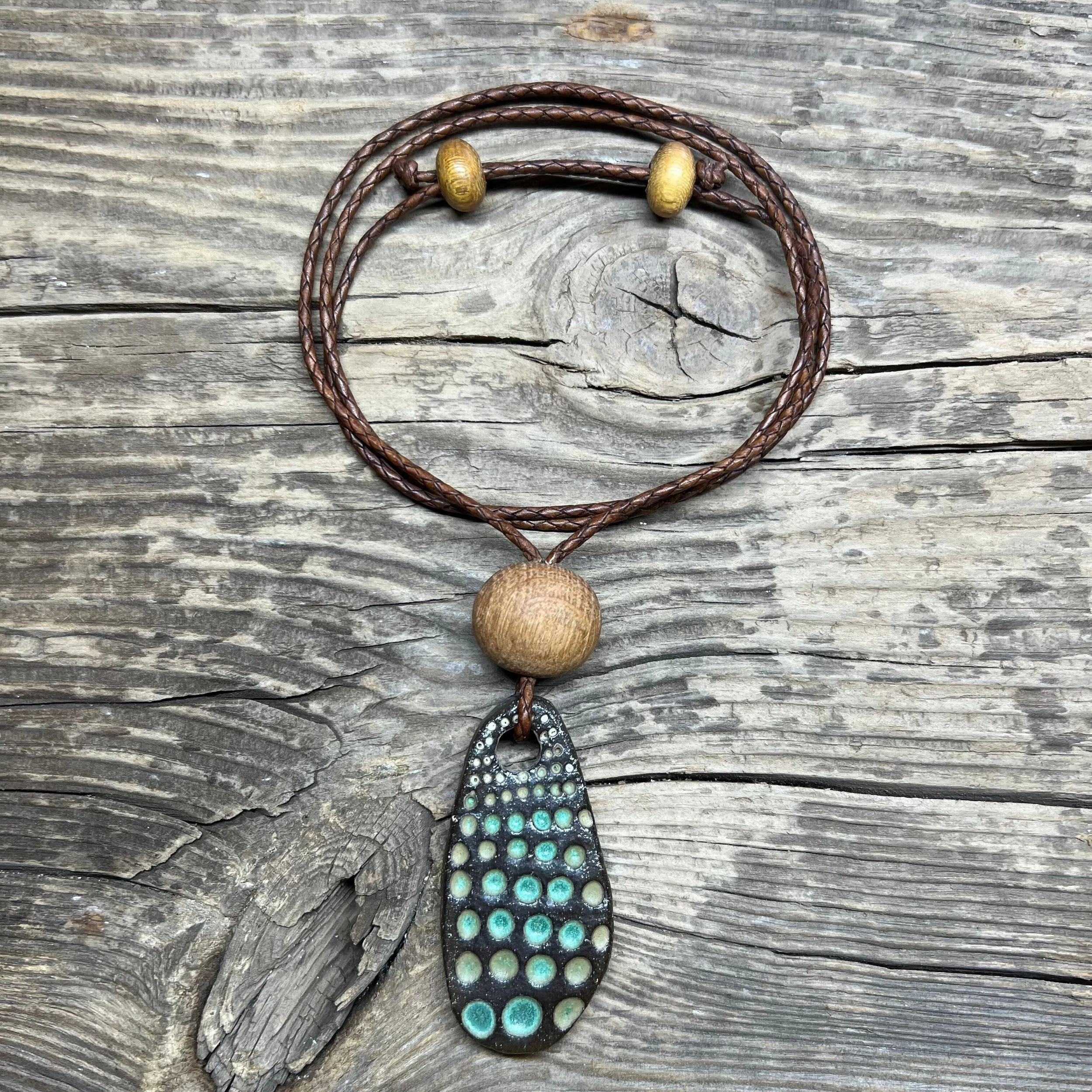 a dark stoneware clay pendant, wooden bead with a green glaze inlay