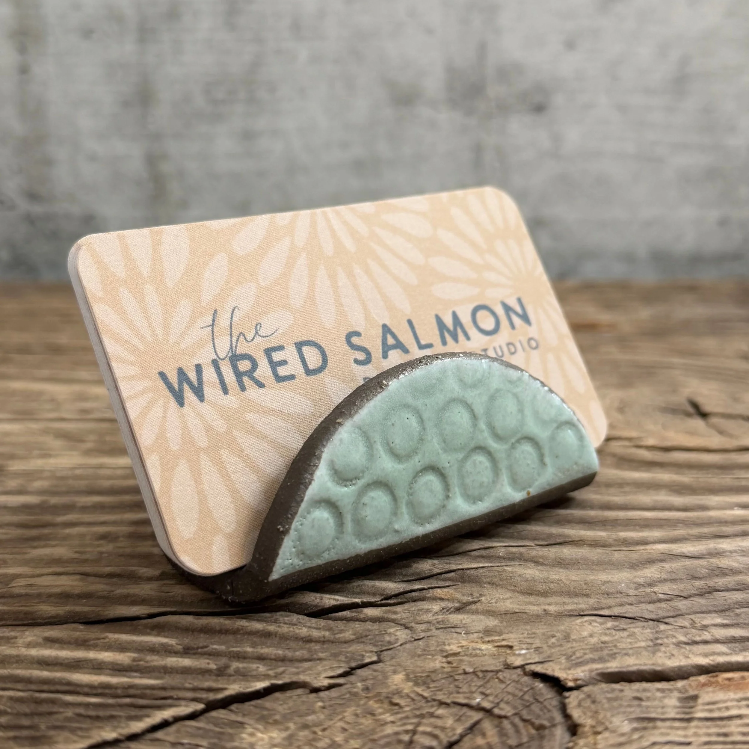 A textured handmade ceramic business card holder made from black clay with a mint finish.