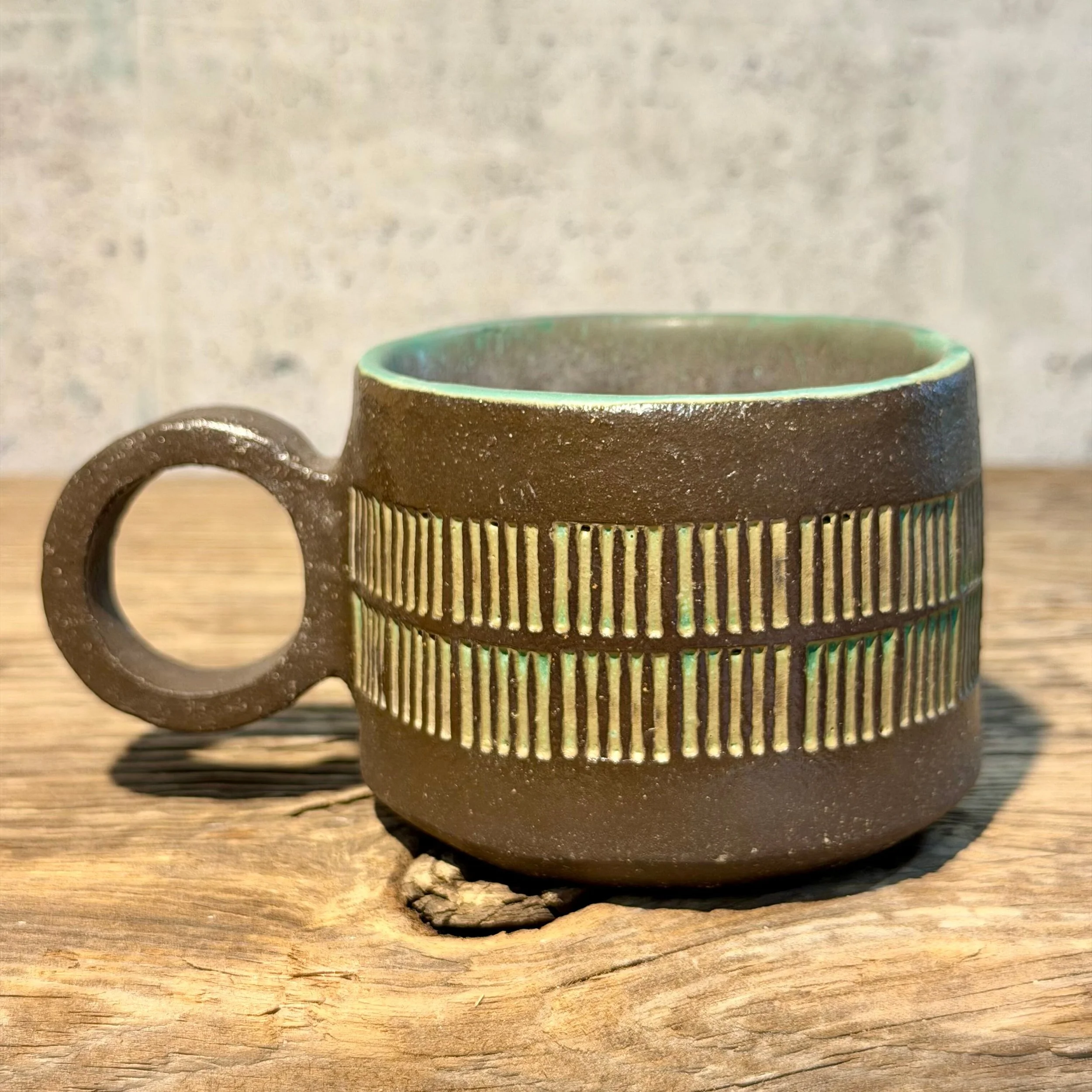 dark stoneware clay, finished in a beautiful mottled green glaze on the inside and inlaid on the outside