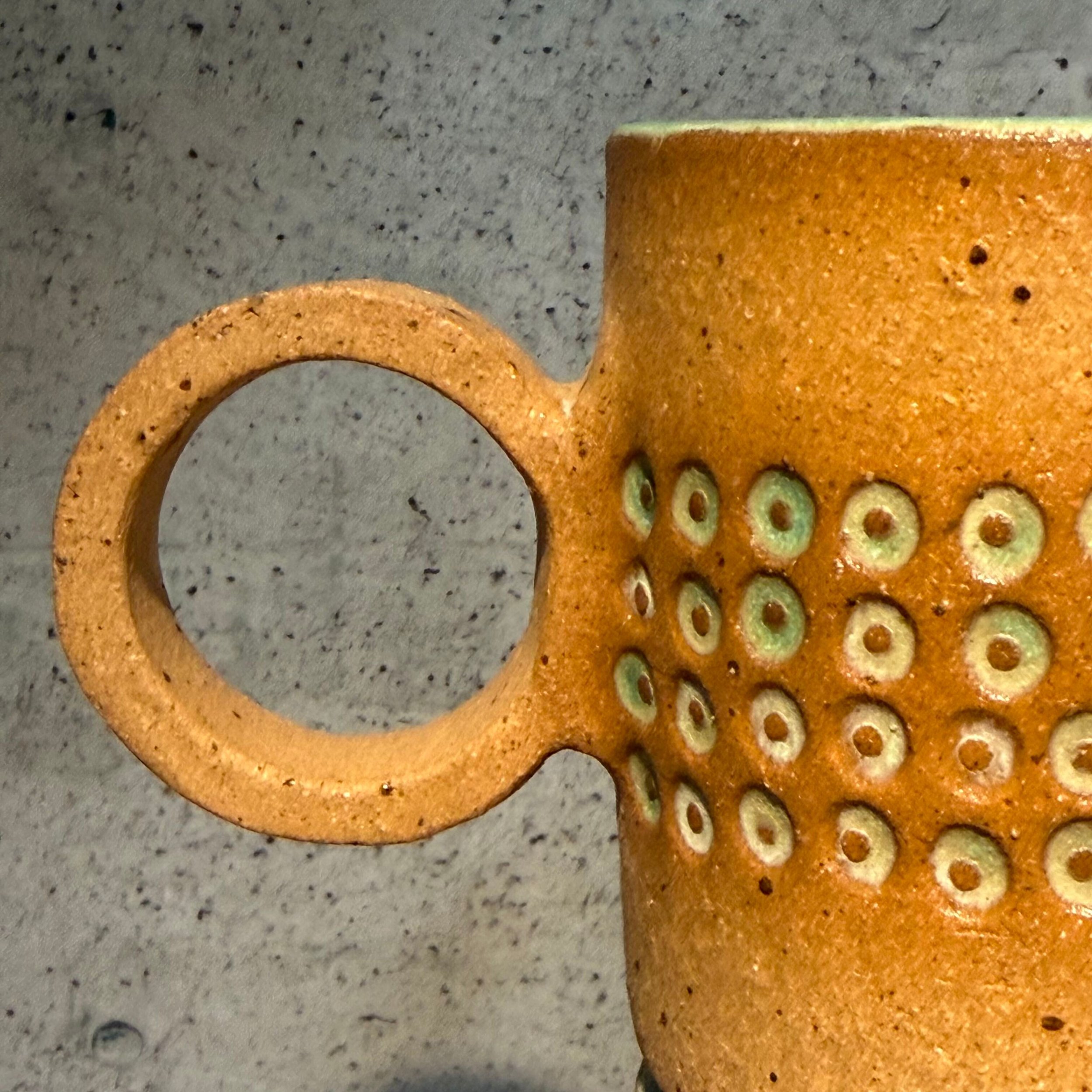 handcrafted cup, made from speckled stoneware clay.   Finished in a beautiful satin patina green glaze on the inside, inlaid on the outside with a comfortable circular handle.