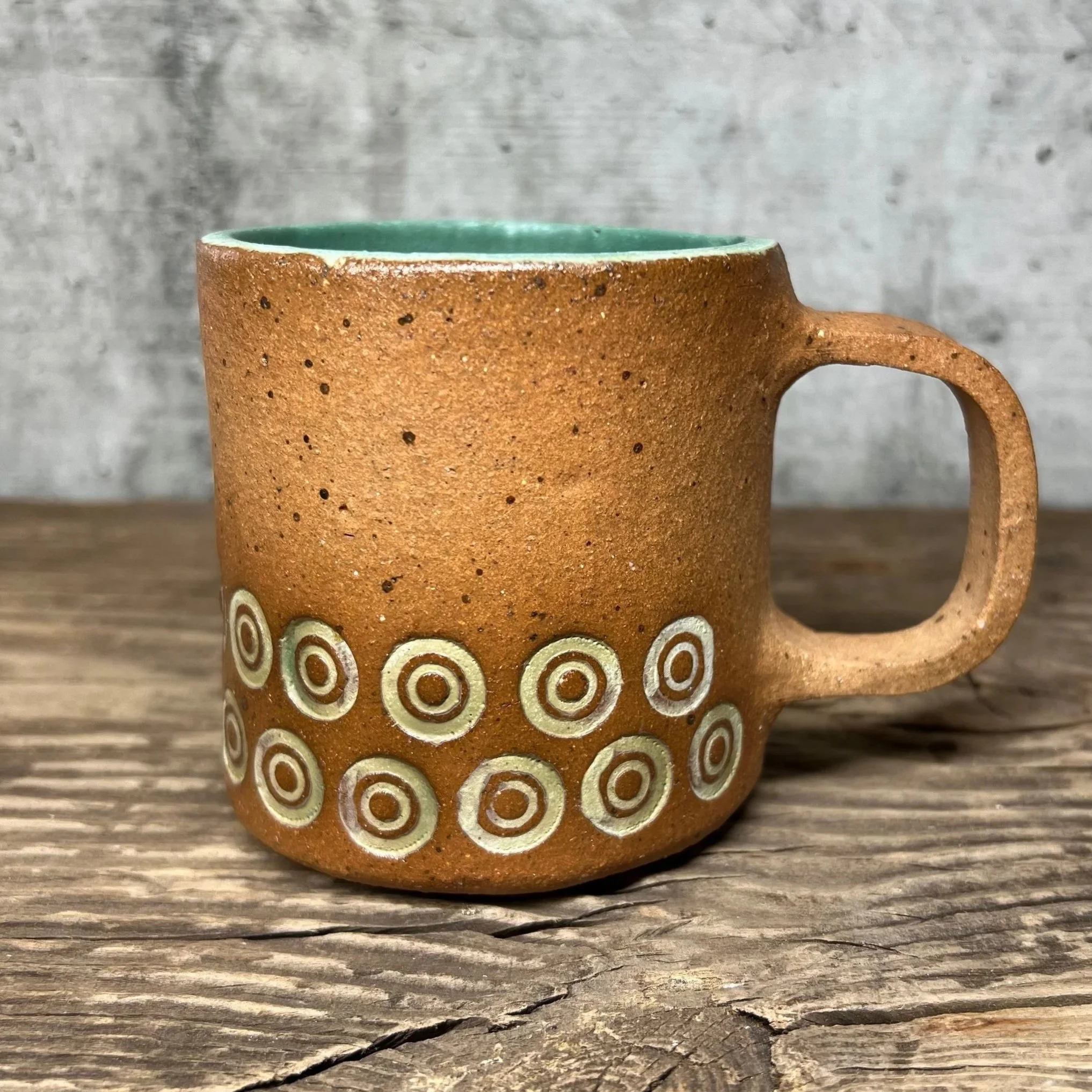 handcrafted cup, made from speckled stoneware clay.   Finished in a beautiful green glaze on the inside with an inlay of circles on the outside.