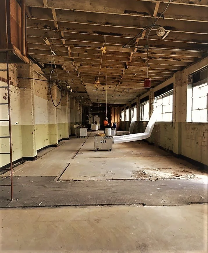 Interior of a room under construction with exposed ductwork, wooden paneling, boxes, and ladders.
