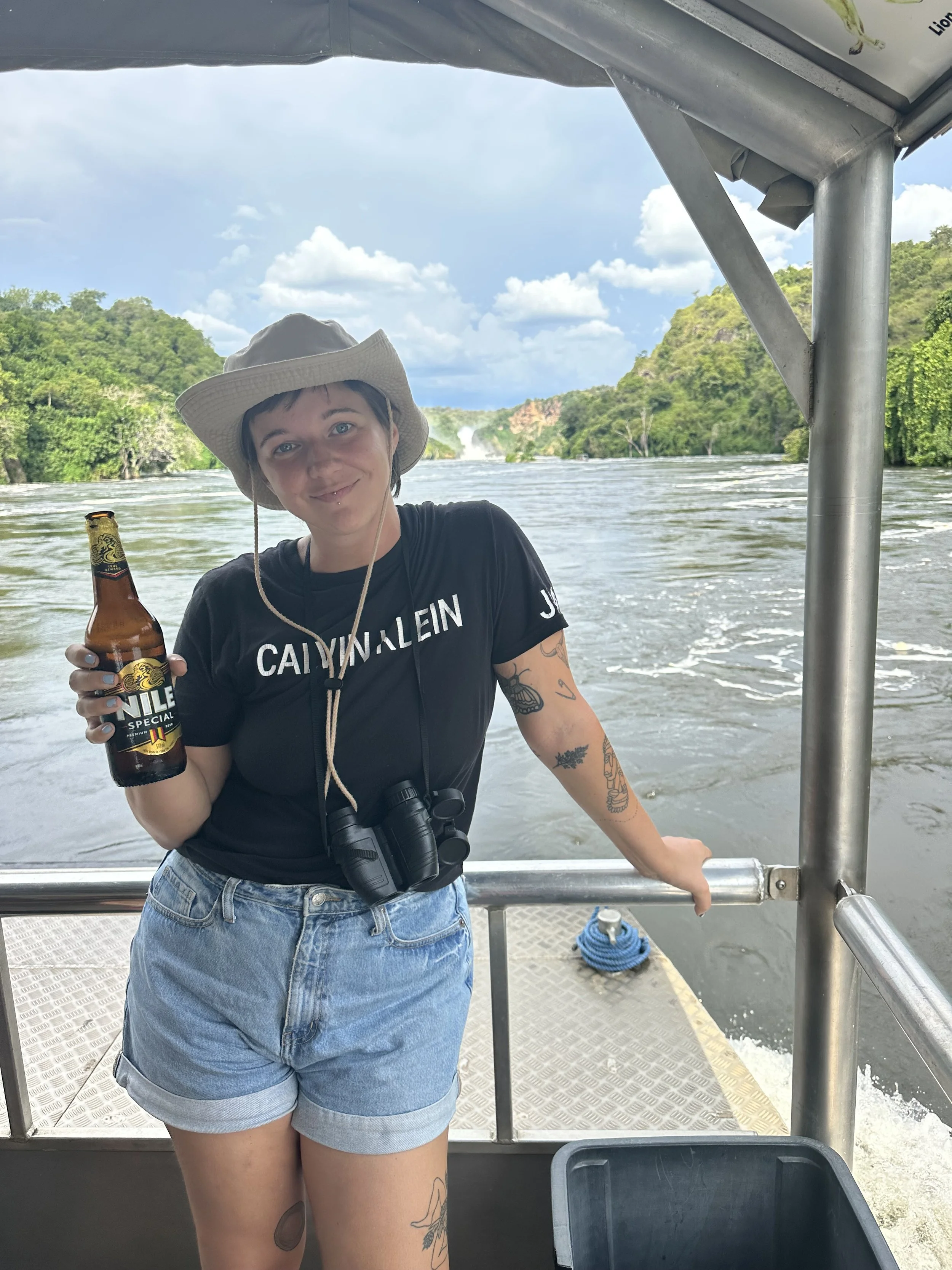 Woman drinking Nile Beer on the Nile River during Ugandan Safari to see Africa's Big Five